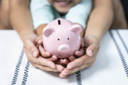 a parent and child holding a piggy bank