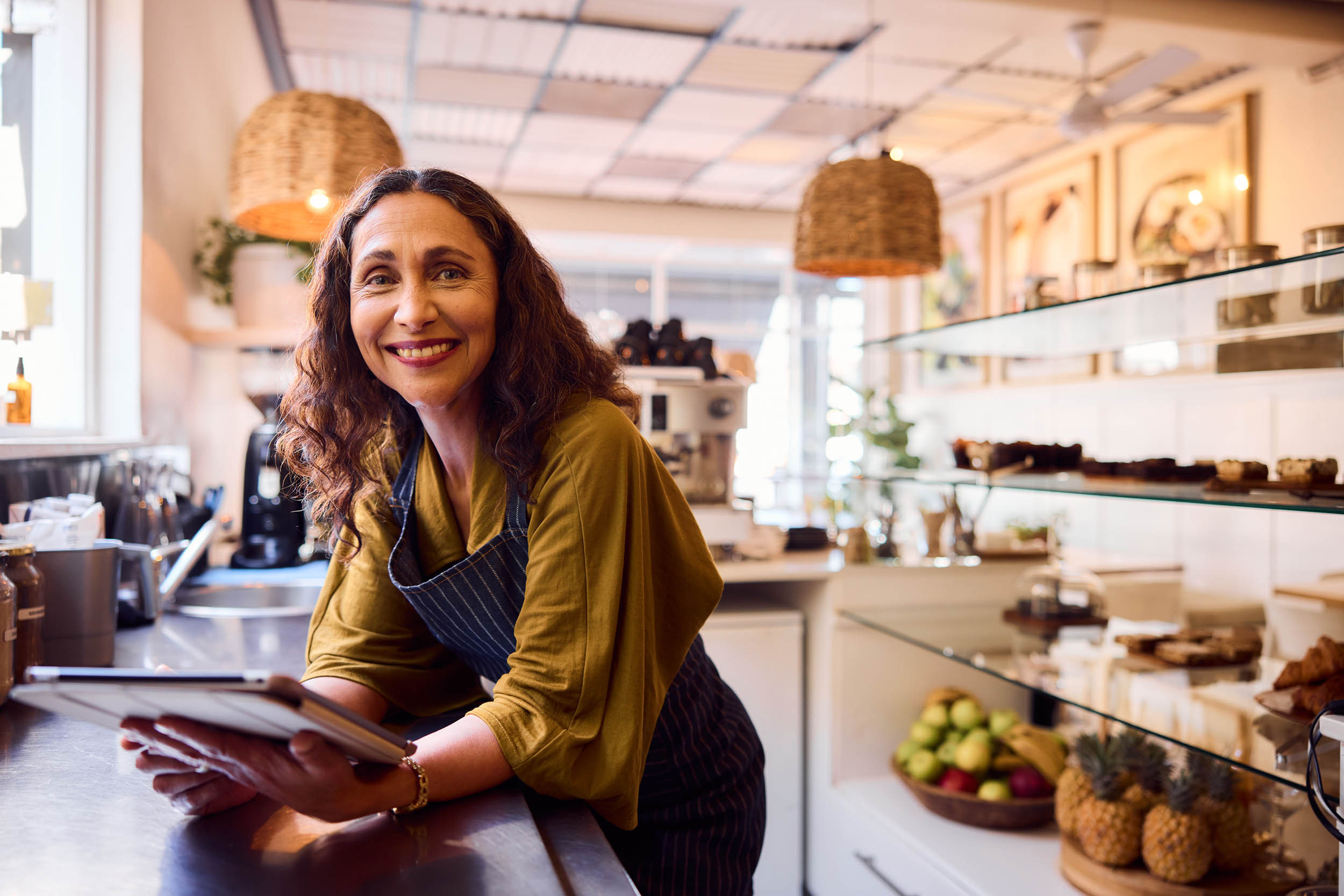 a smiling bakery owner holding a tablet