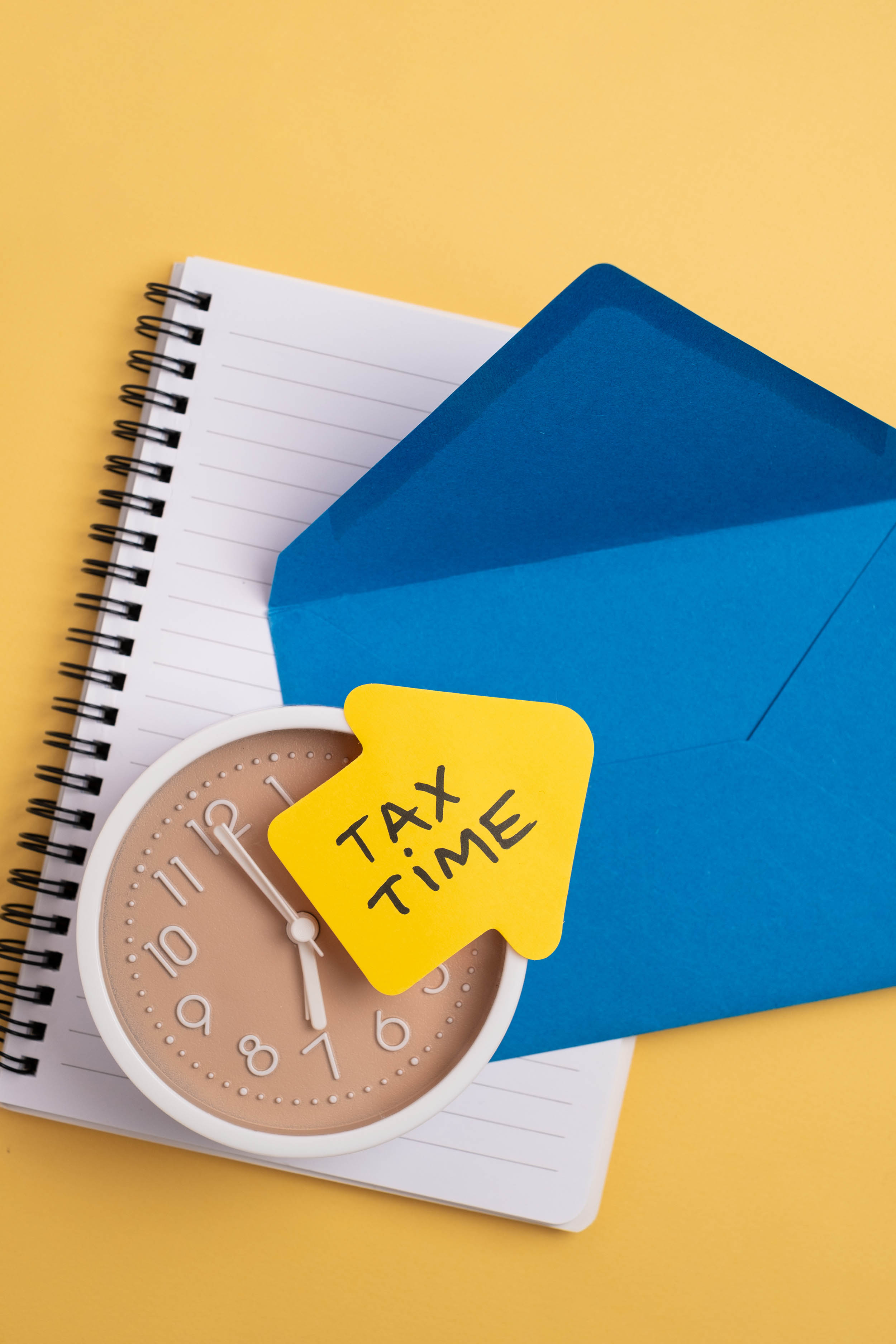 Clock resting on tax forms highlighting the concept of due dates