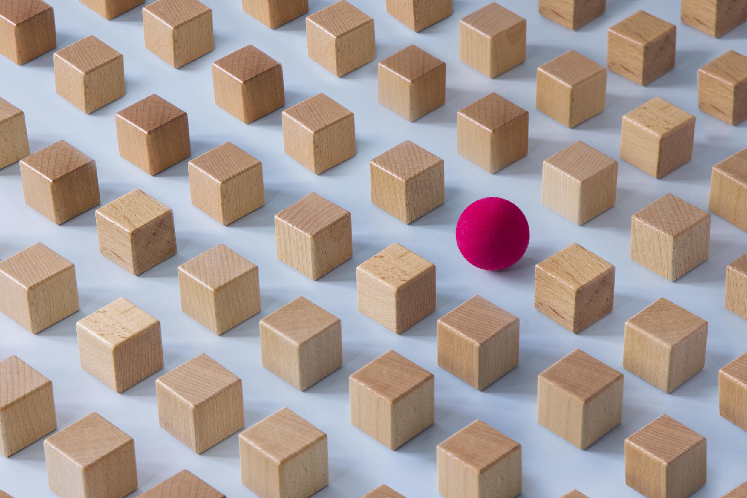 Strategic placement of a red ball among wooden blocks representing targeted tax strategies