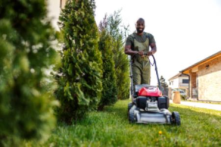 smiling man pushing lawn mower in yard