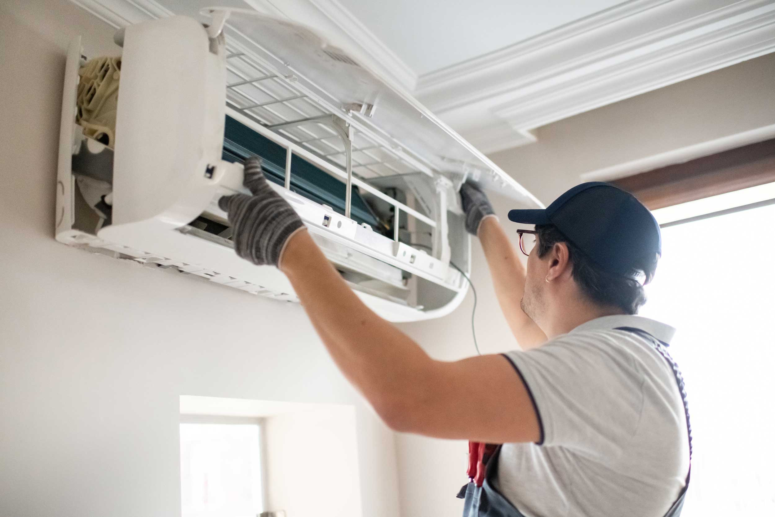 man working on air conditioning unit inside home