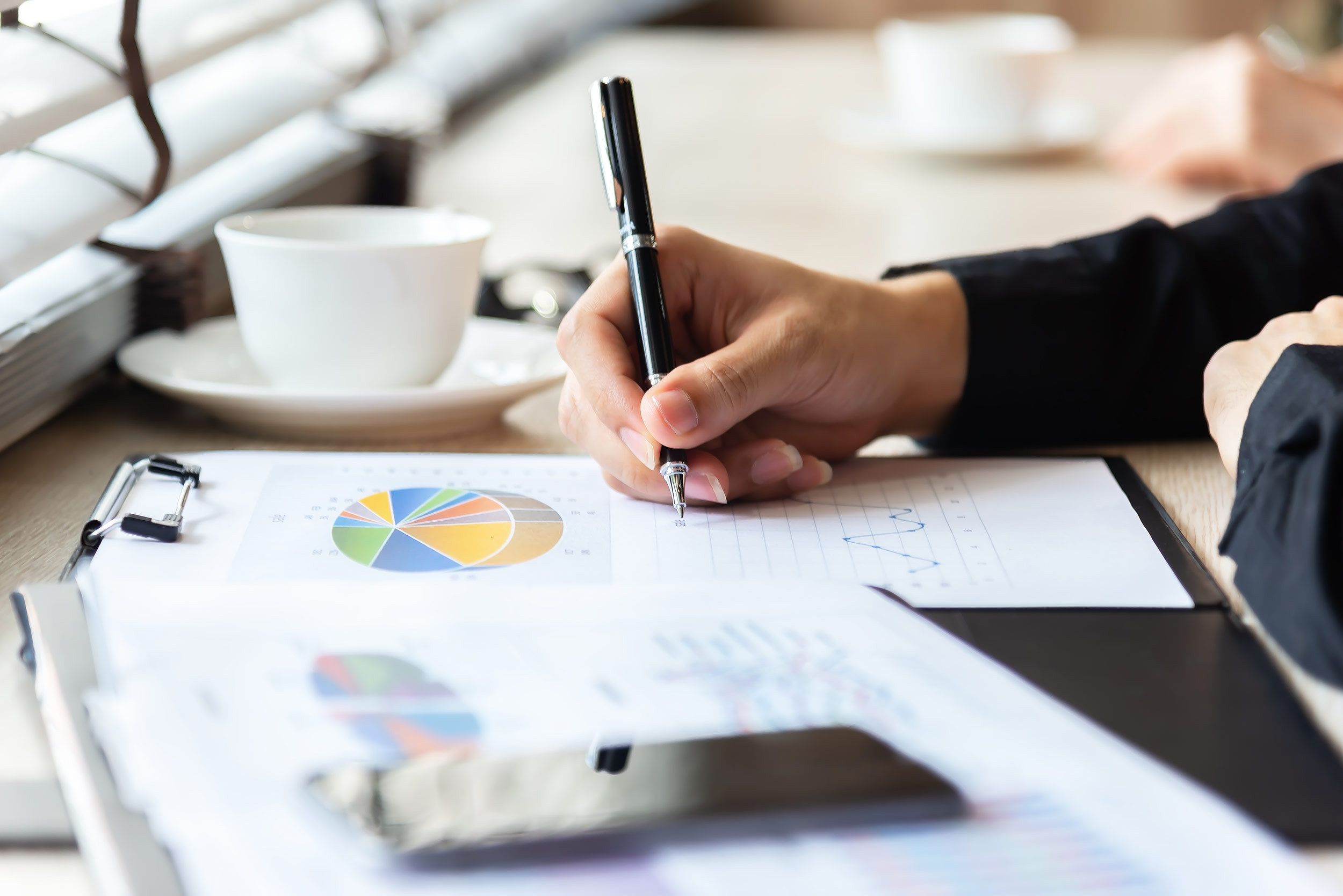 Accountant analyzes and writes on charts at desk