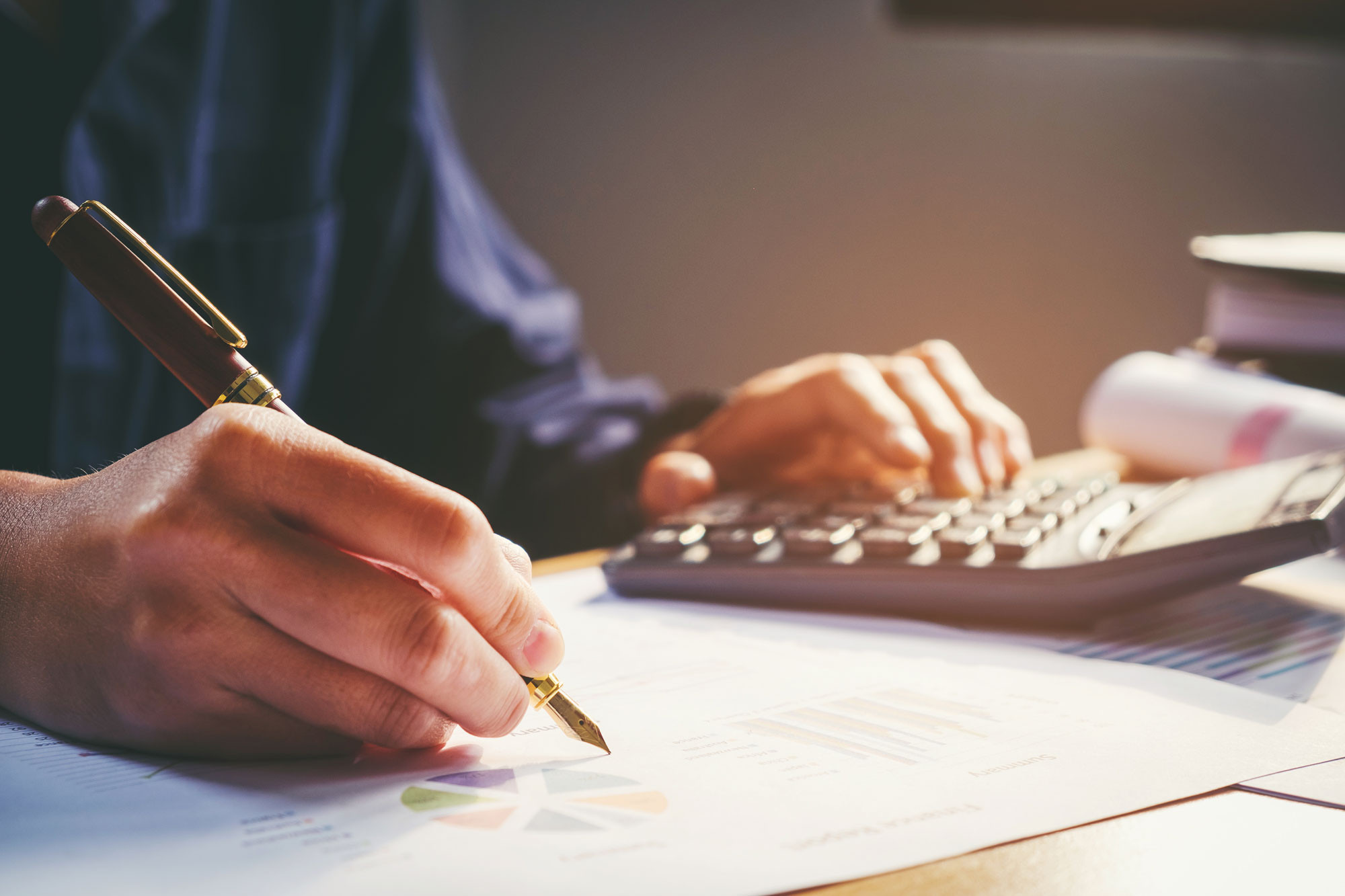 Accountant sitting at a desk writing while using a calculator