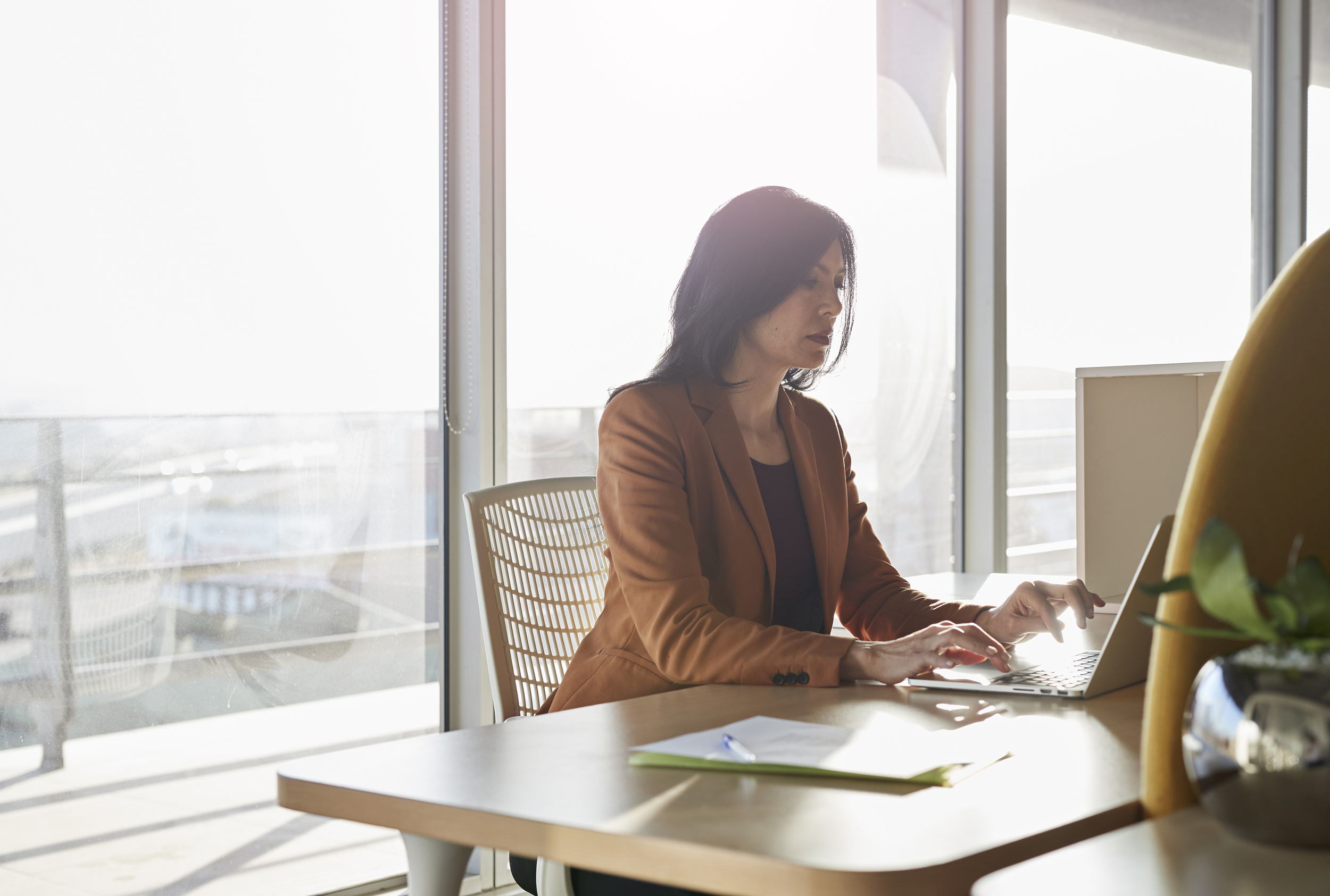 A female business woman sits at her office desk, typing