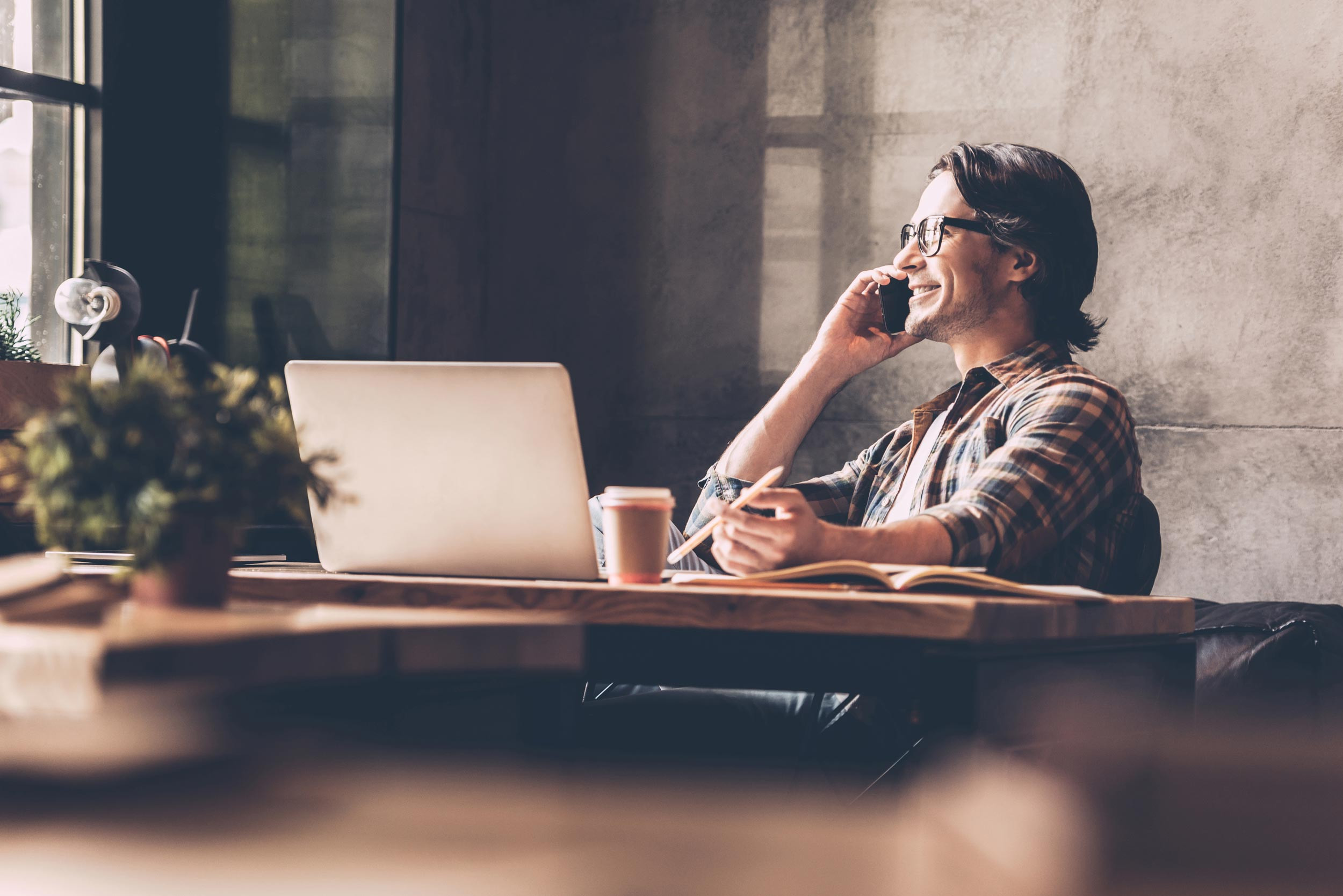 Small business owner answers her phone at her desk in her home office.