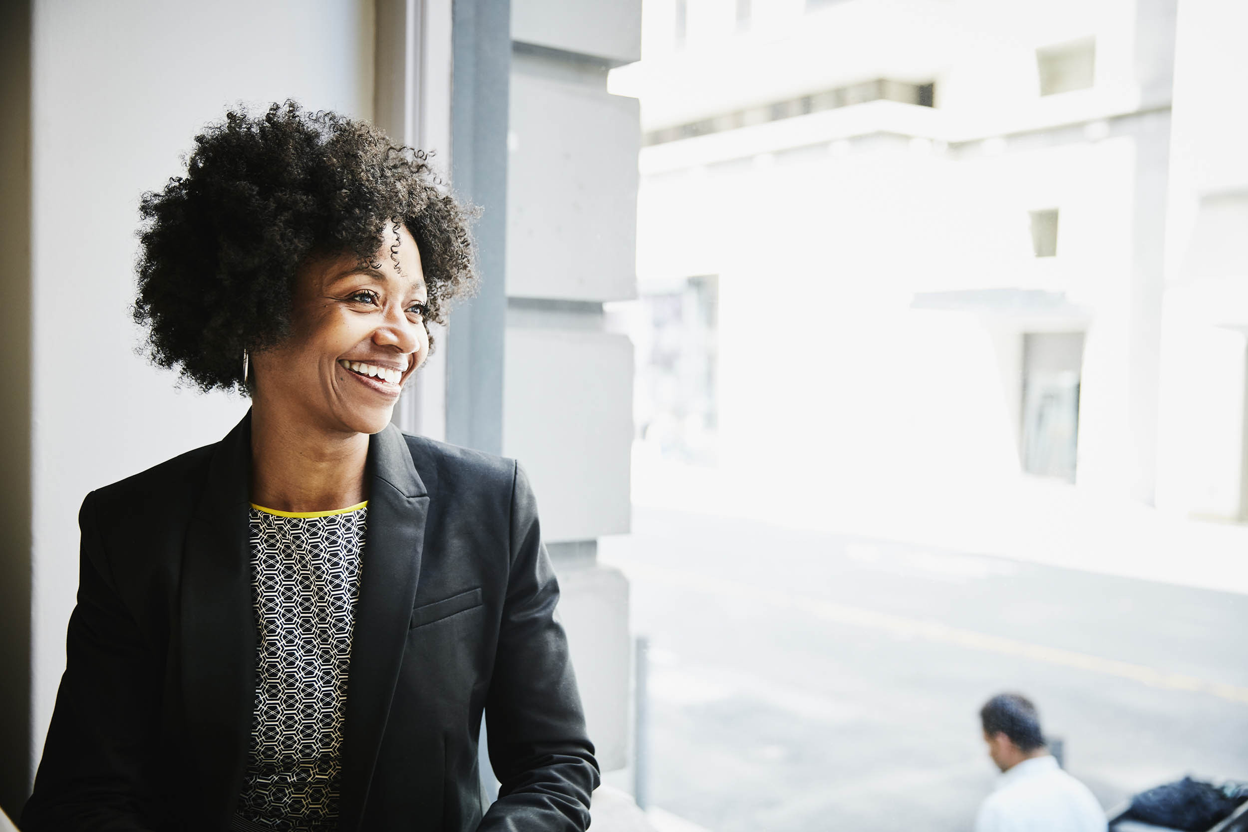 African American businesswoman smiles as she looks out the window.