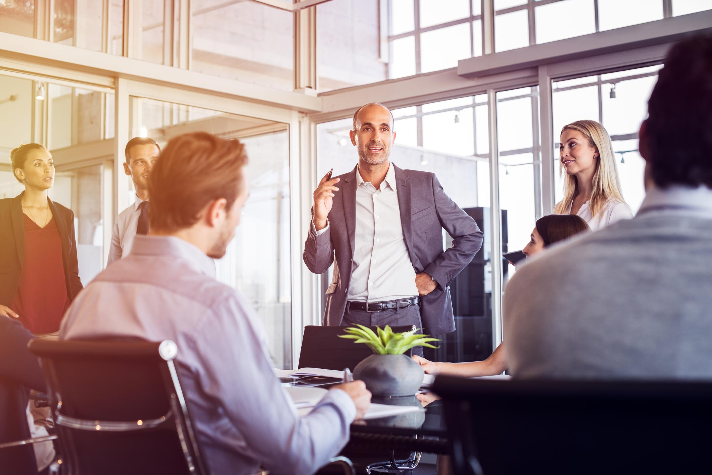 A businessman stands and lectures his coworkers during a business meeting.