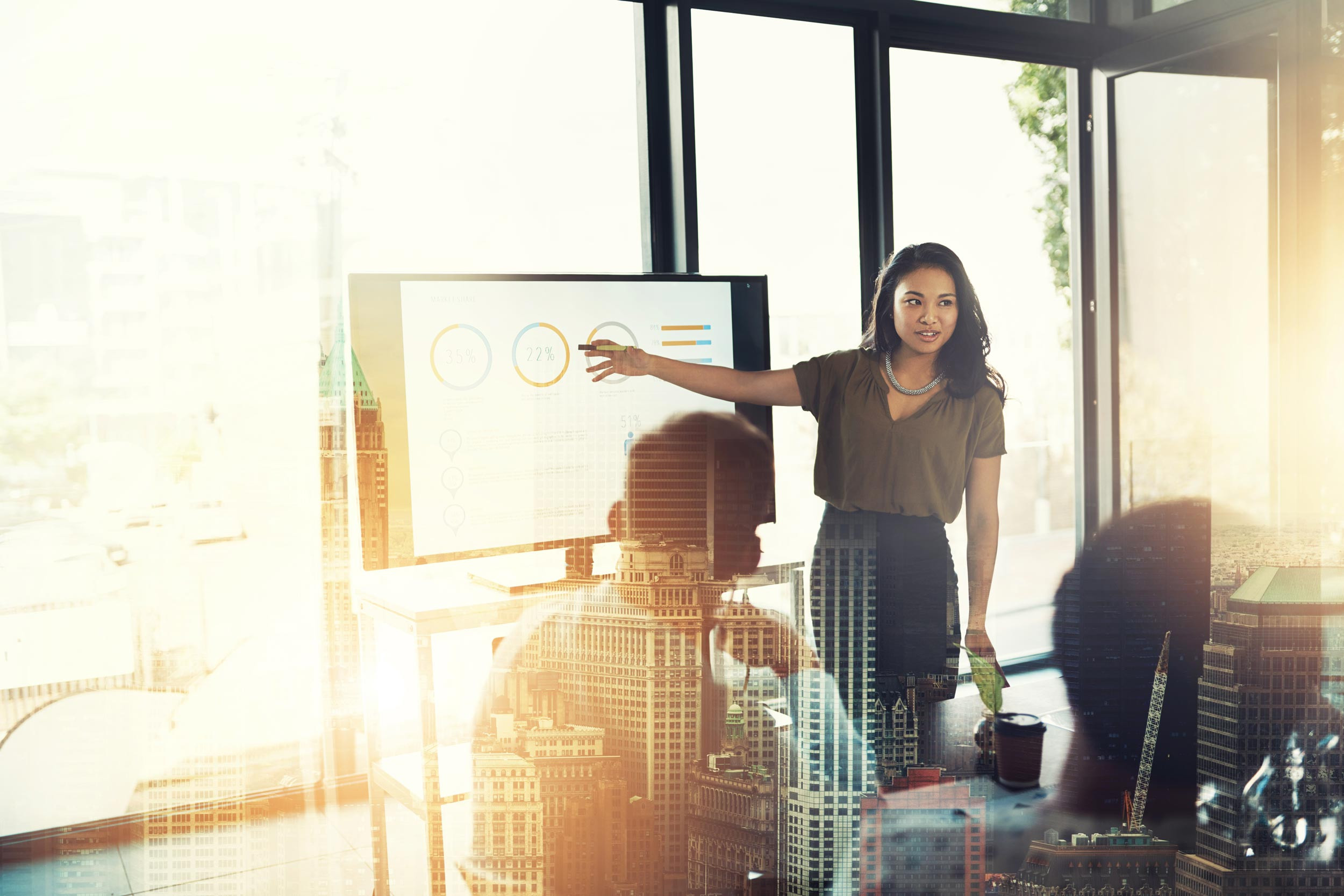 Businesswoman reviews data on a monitor with her coworkers in a business meeting.