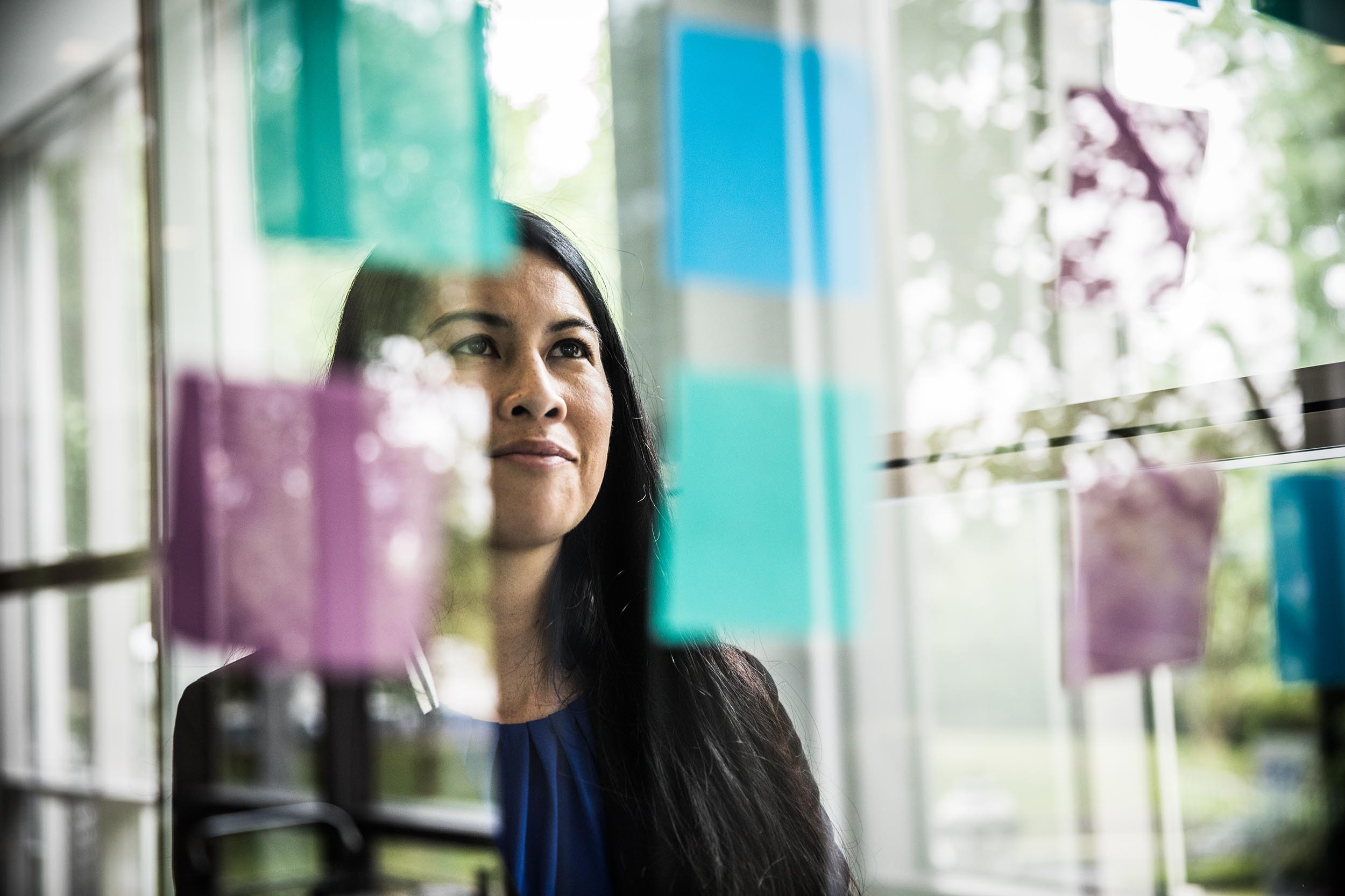 Business professional inspired while looking at notes on clear window