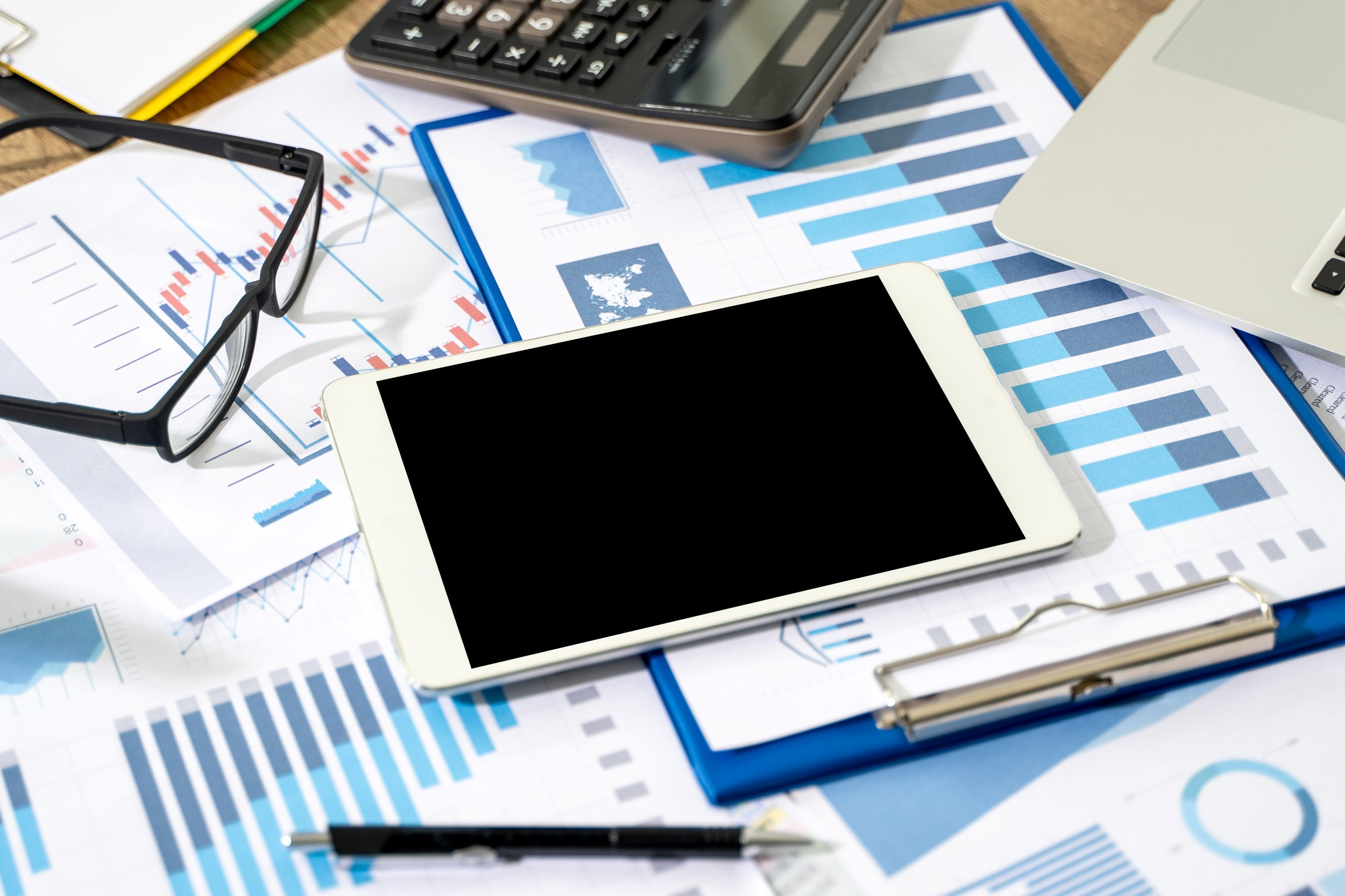 pile of accounting documents and clipboard under a tablet and calculator