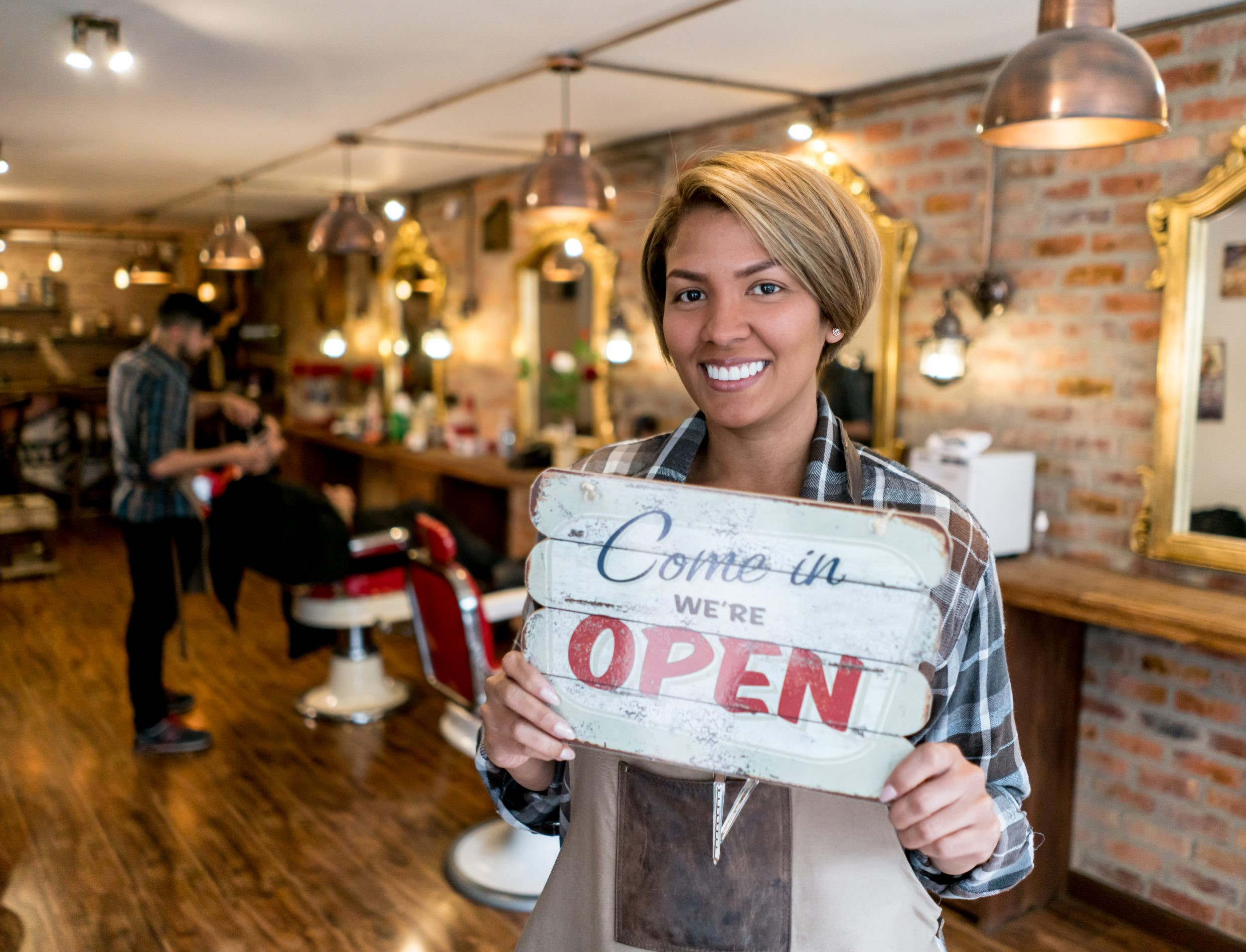 happy barber shop owner holding an open sign