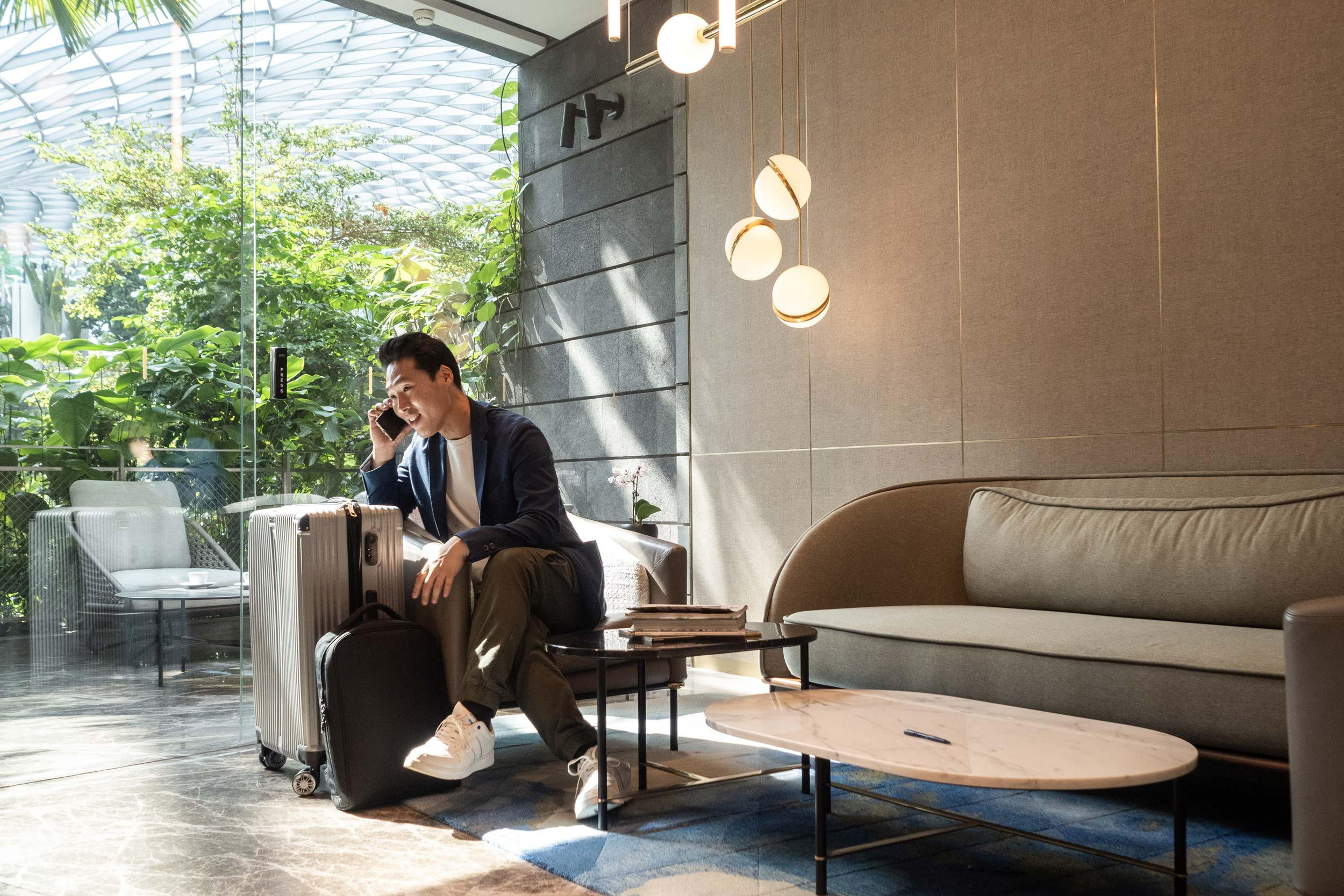 man on the phone with suitcases sitting in a lobby