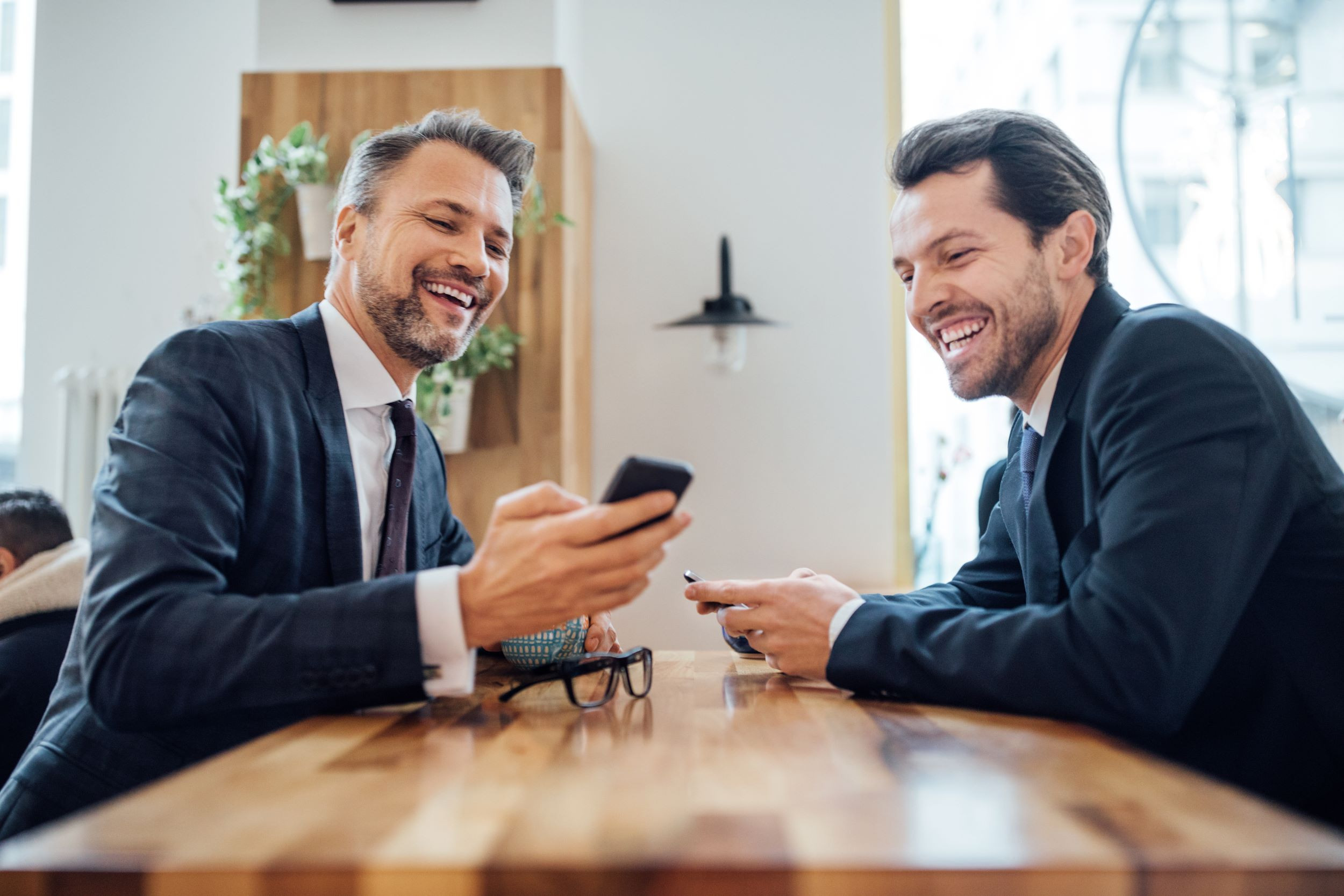 businessman sharing something on his phone to colleague
