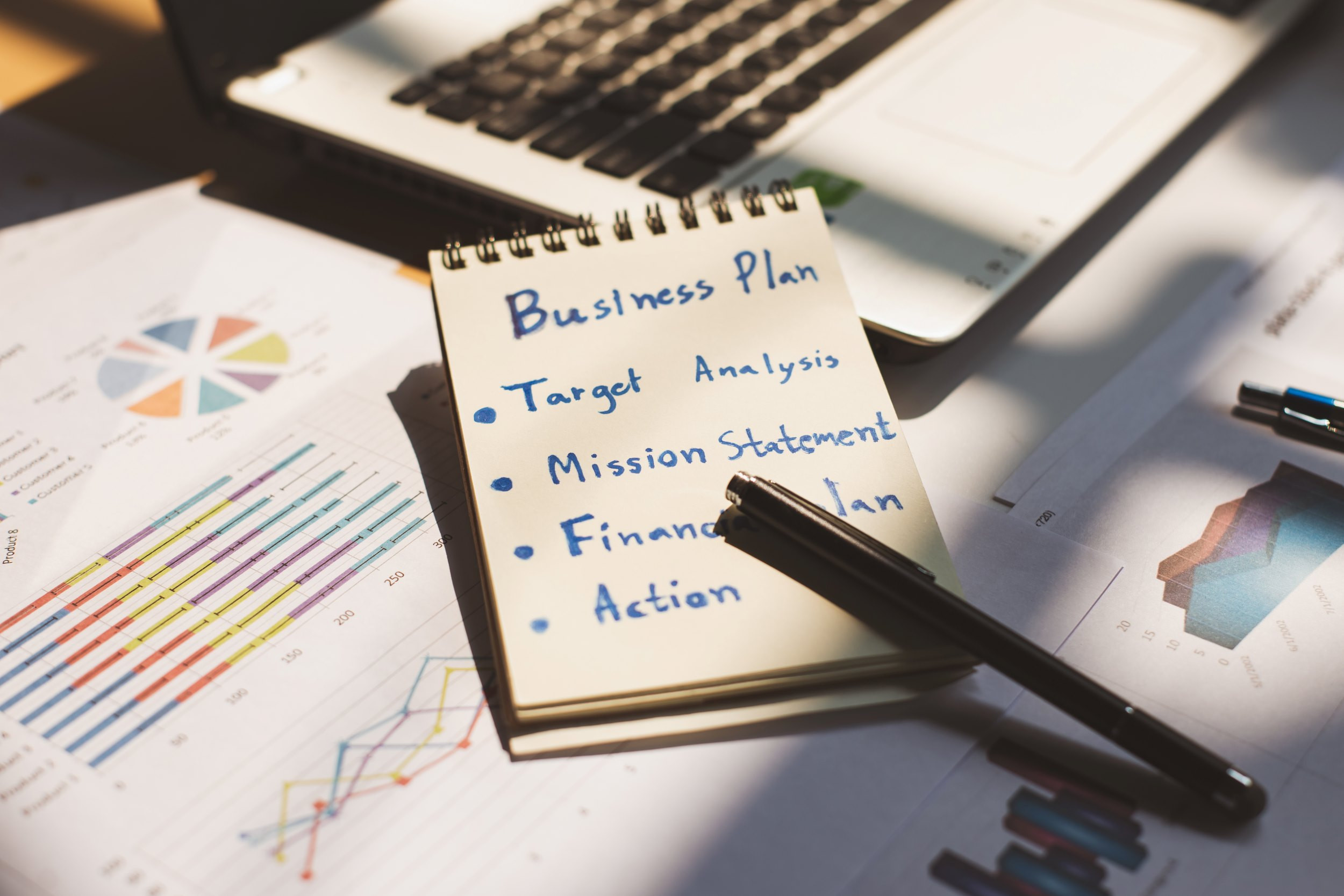 notepad with business plan and financial graphs on a table