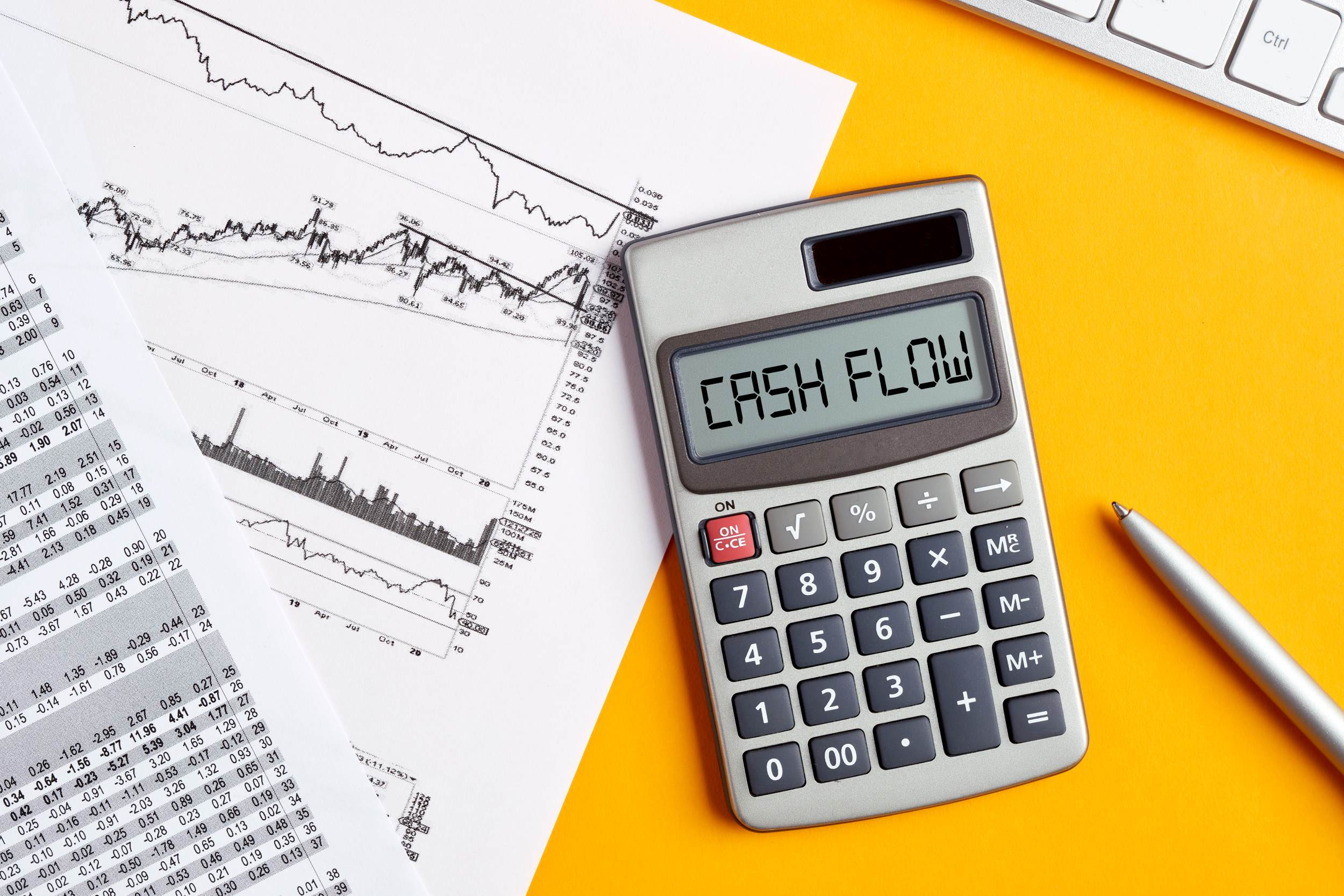 calculator with the words "cash flow" above business graphs