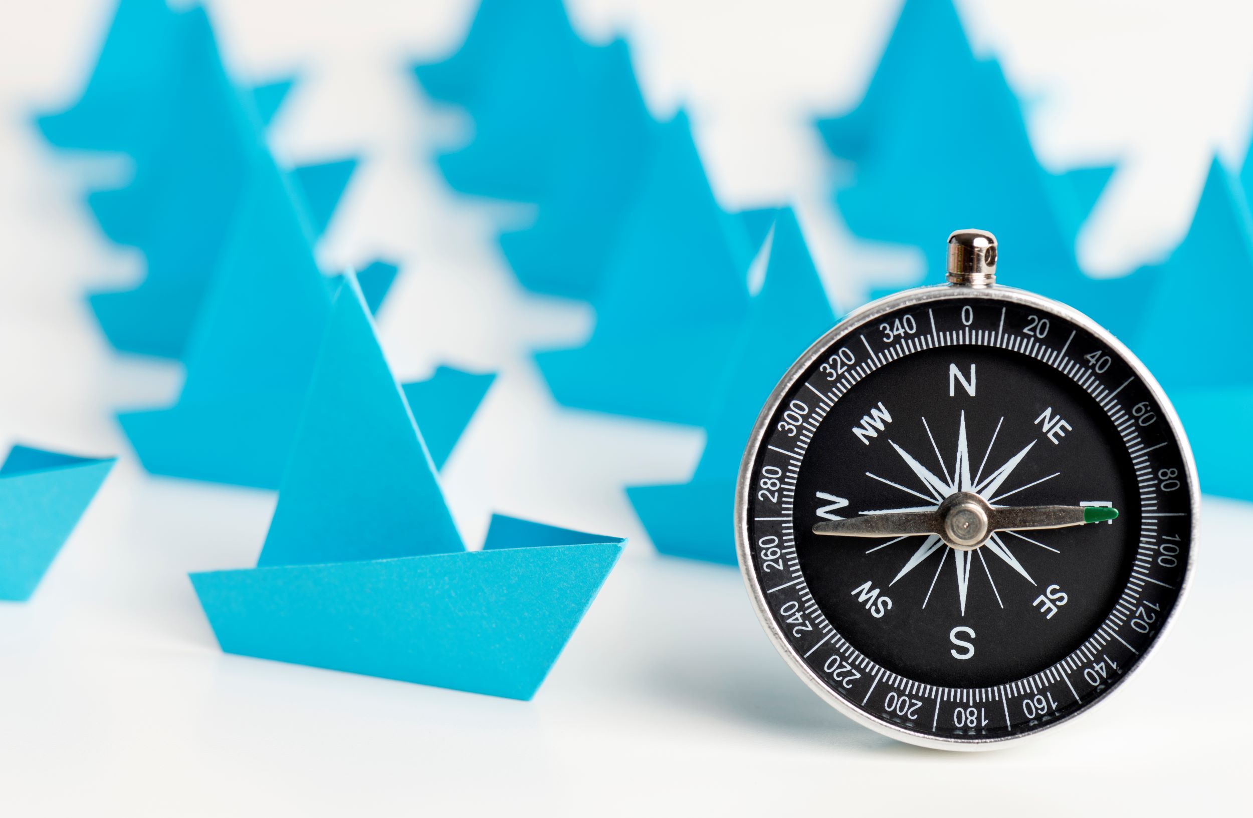Paper boats and a compass showing direction
