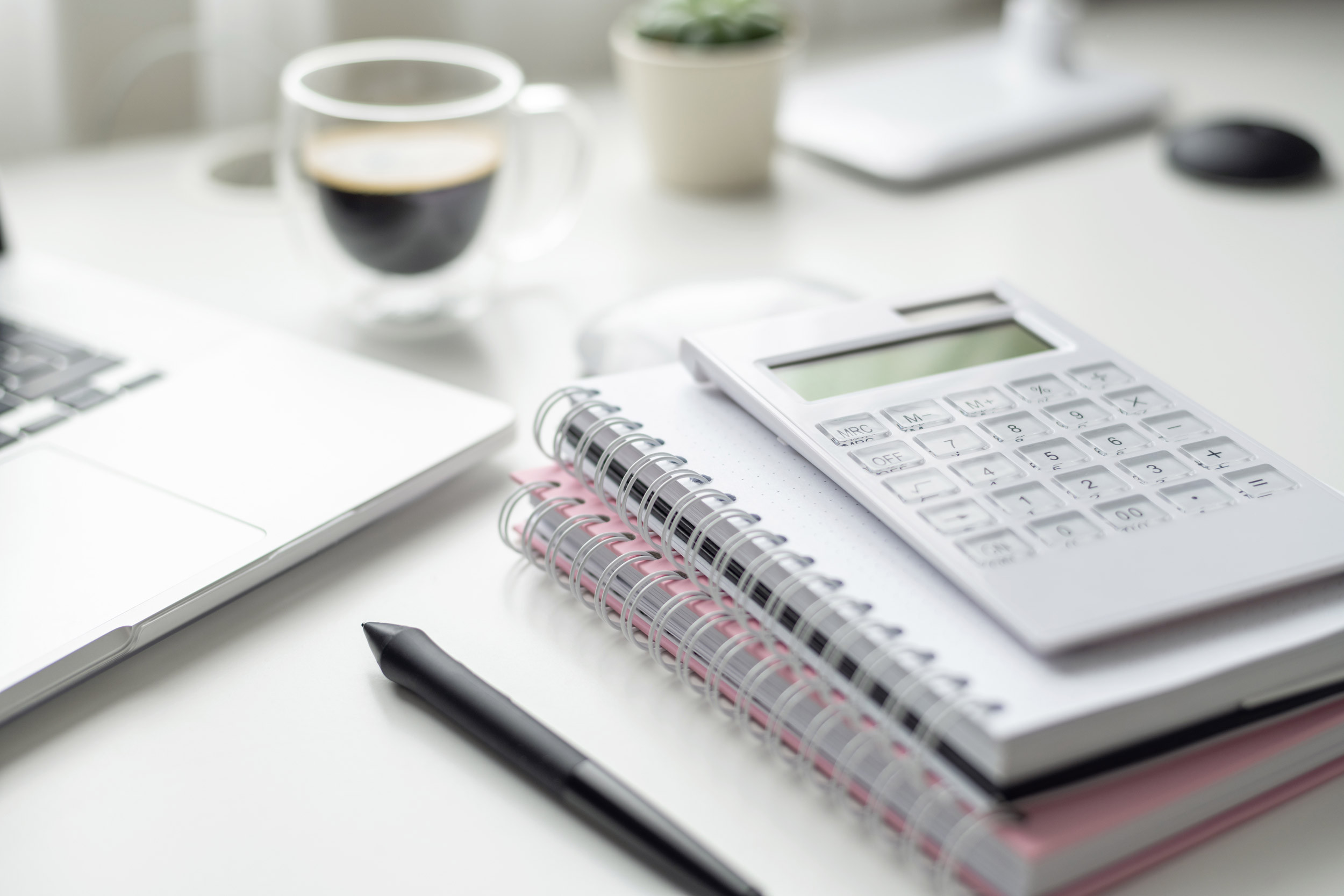 computer, coffee, notebooks and calculator on a desktop