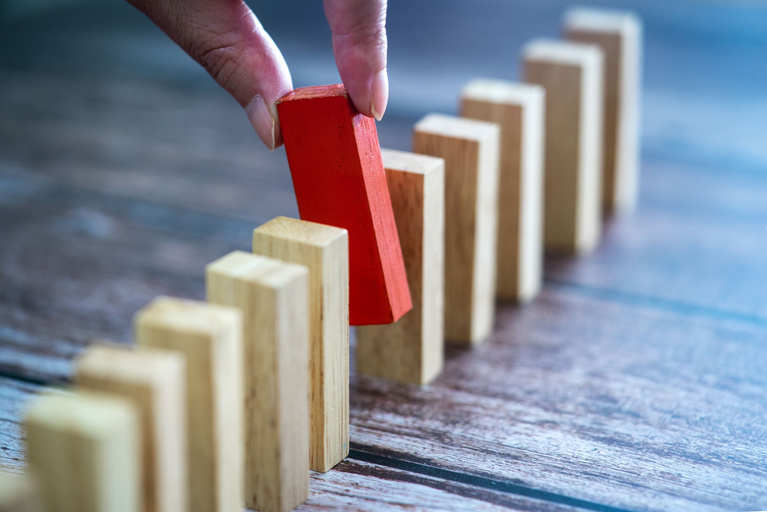 a hand removing a red domino block from the line