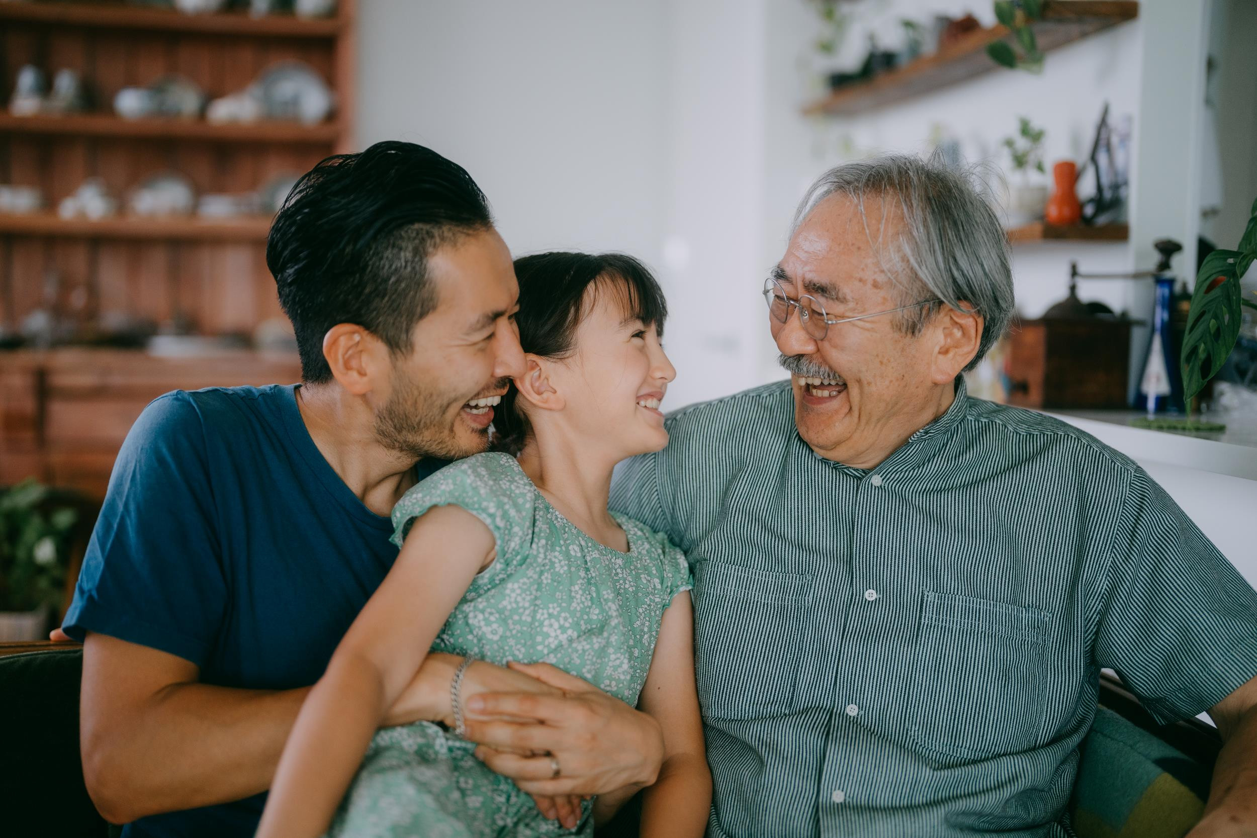 a grandfather, father and child happily sitting together