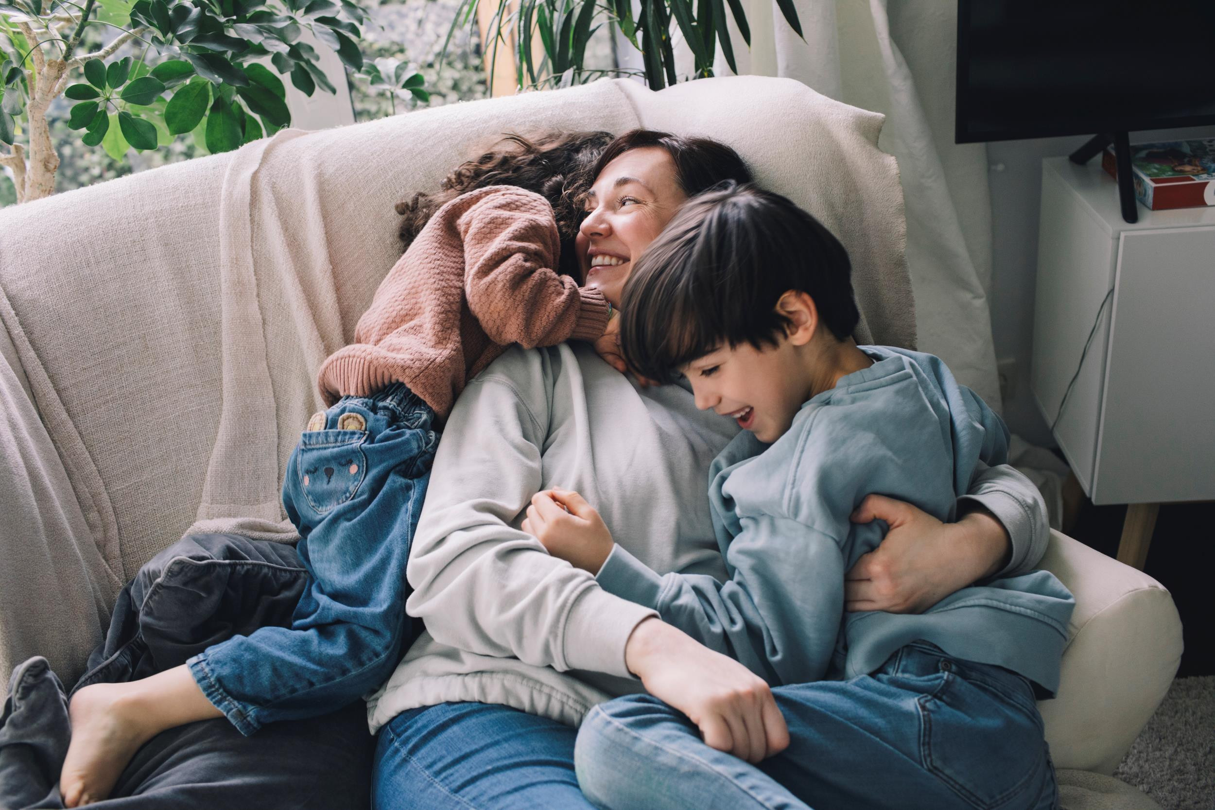 happy children hugging their mother on the couch
