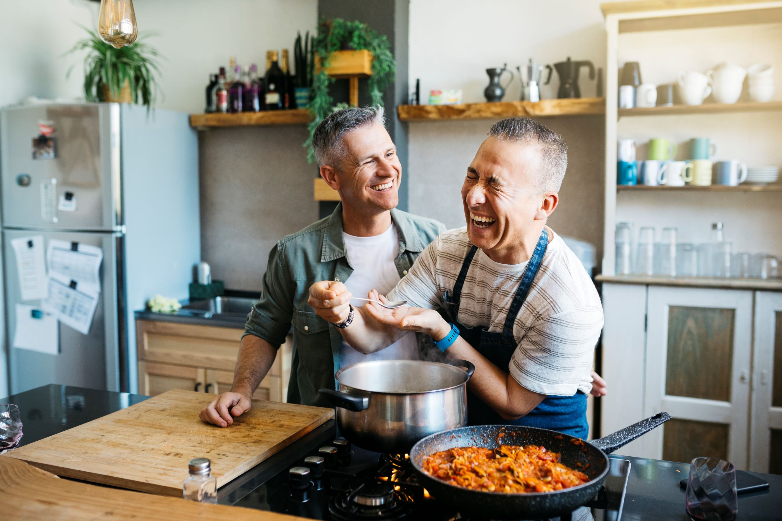 happy LGBTQ couple cooking together at home