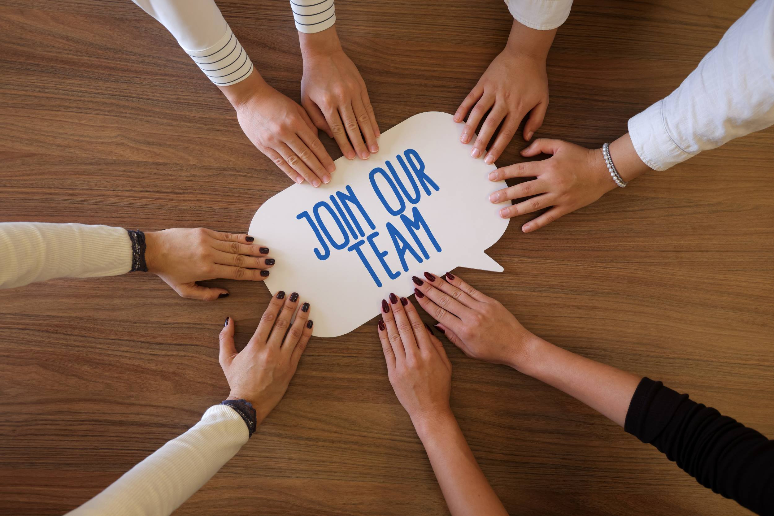 a business team holding a Join Our Team cutout