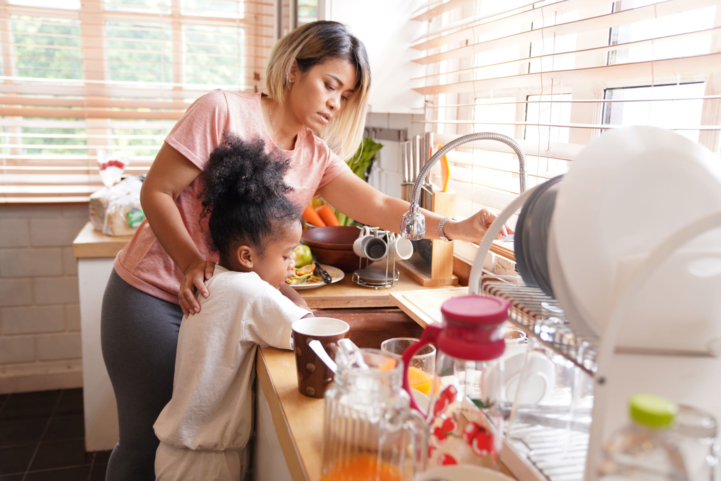 a mother and child washing dishes together