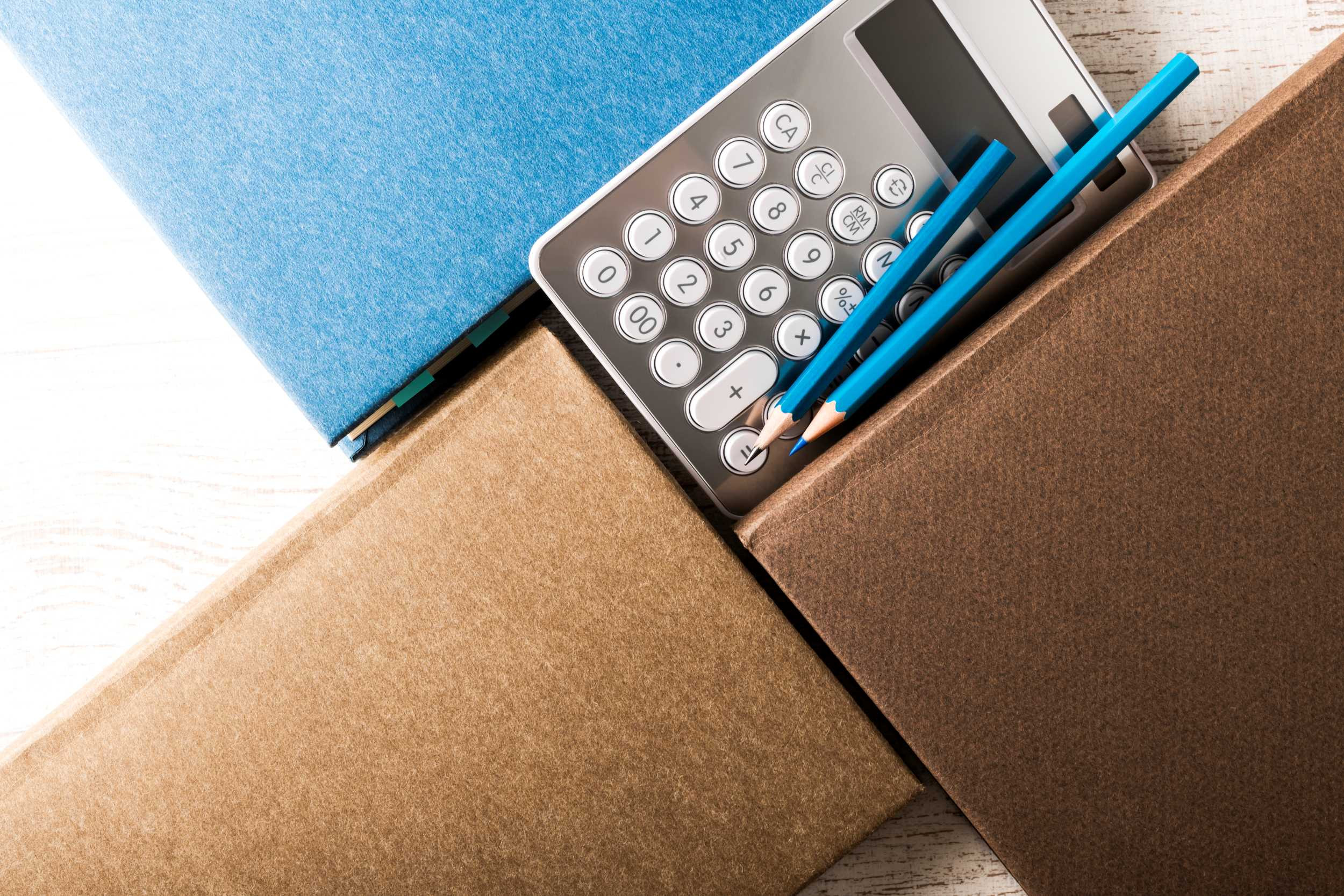 notebooks, calculator and a pen on a desk