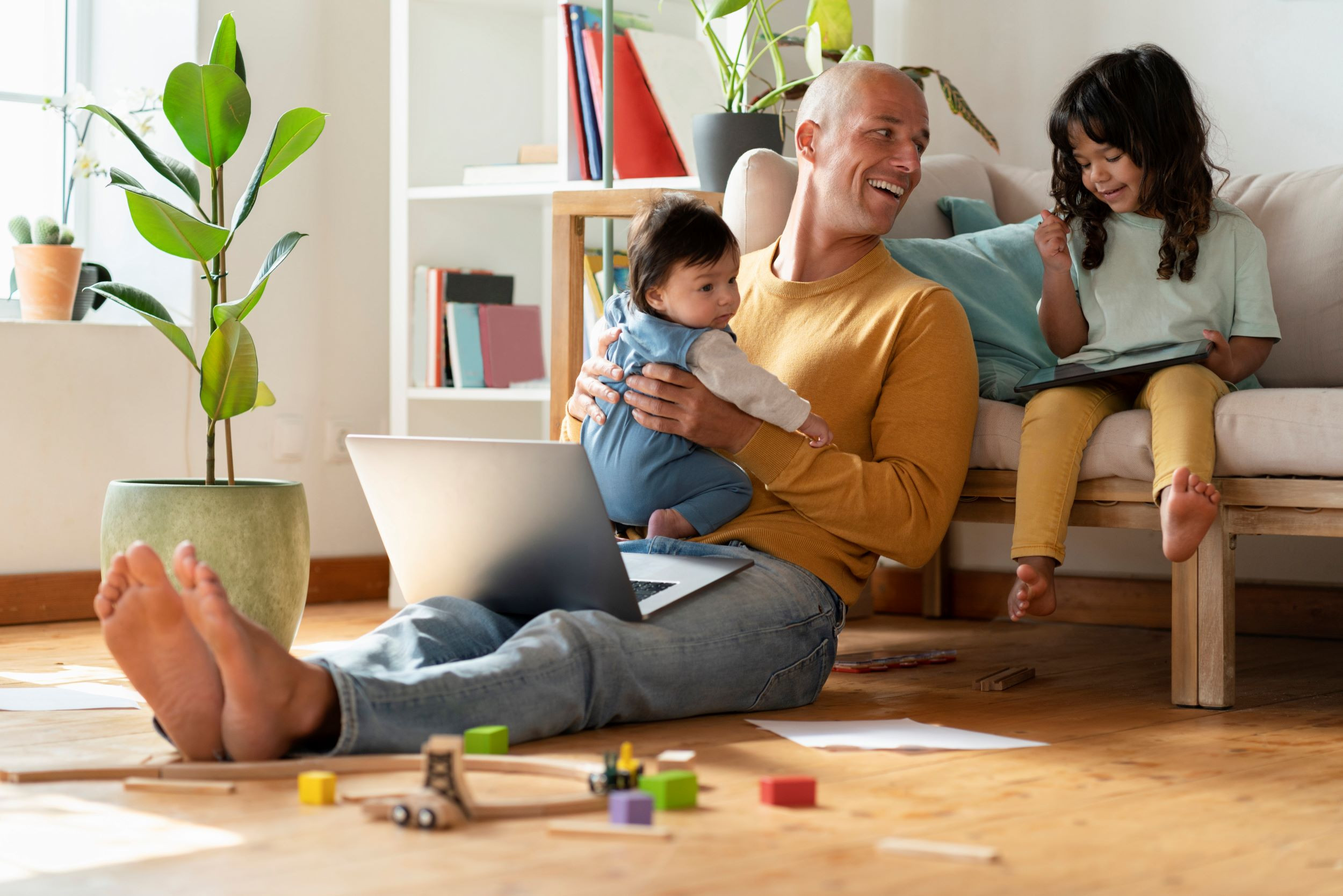 a father working on laptop at home with his children