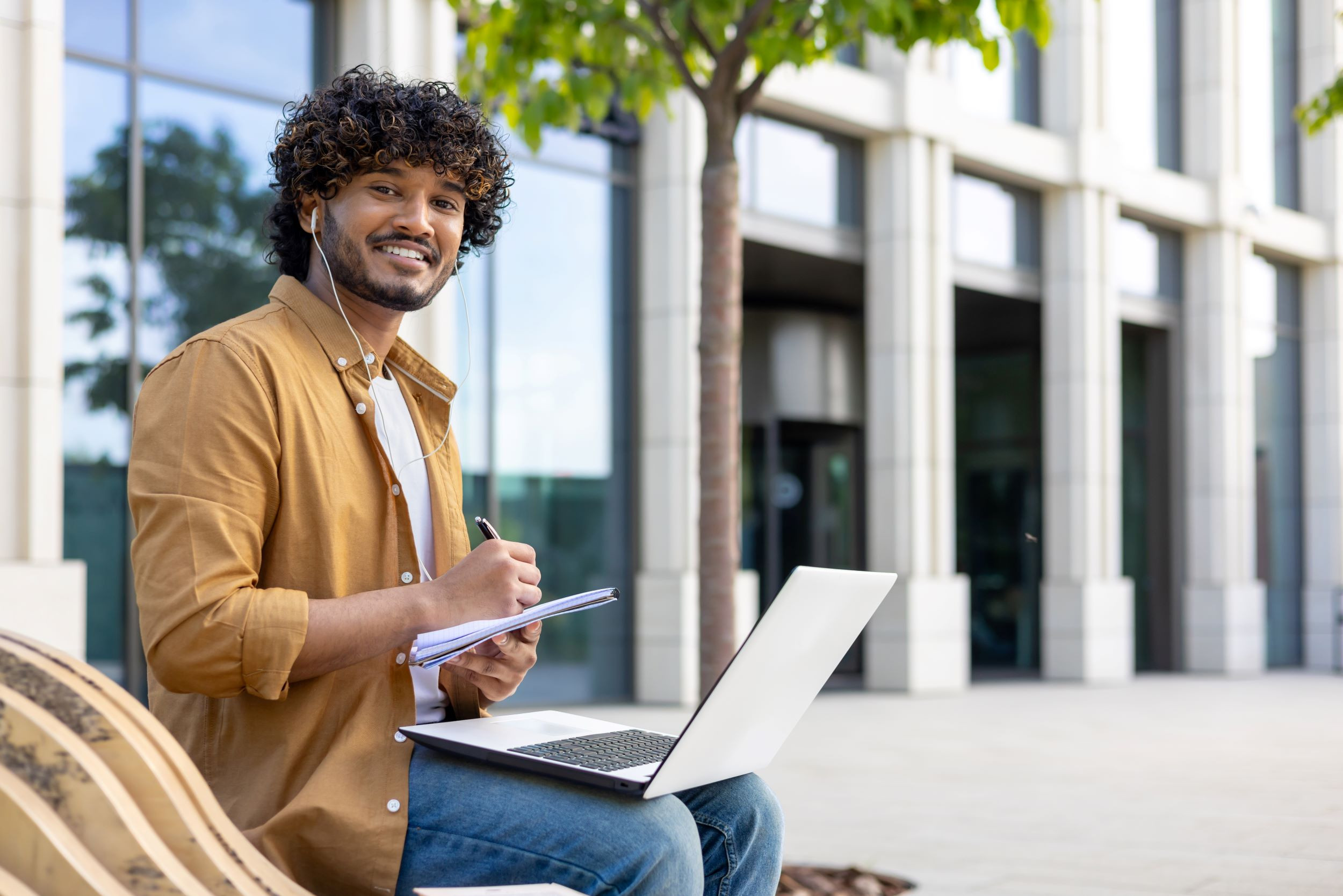 a smiling freelancer working outdoors with a laptop