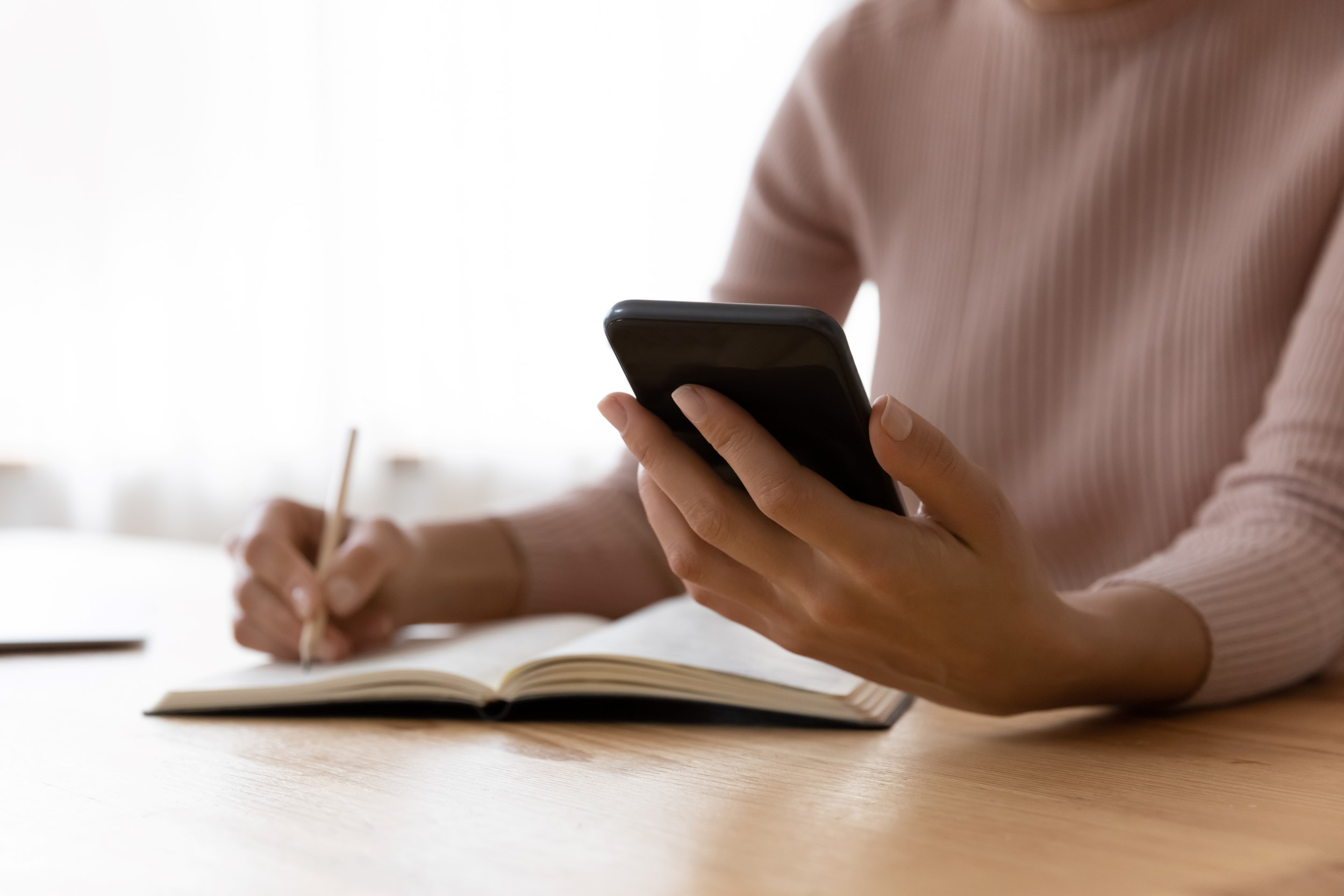 person looking at phone and taking notes