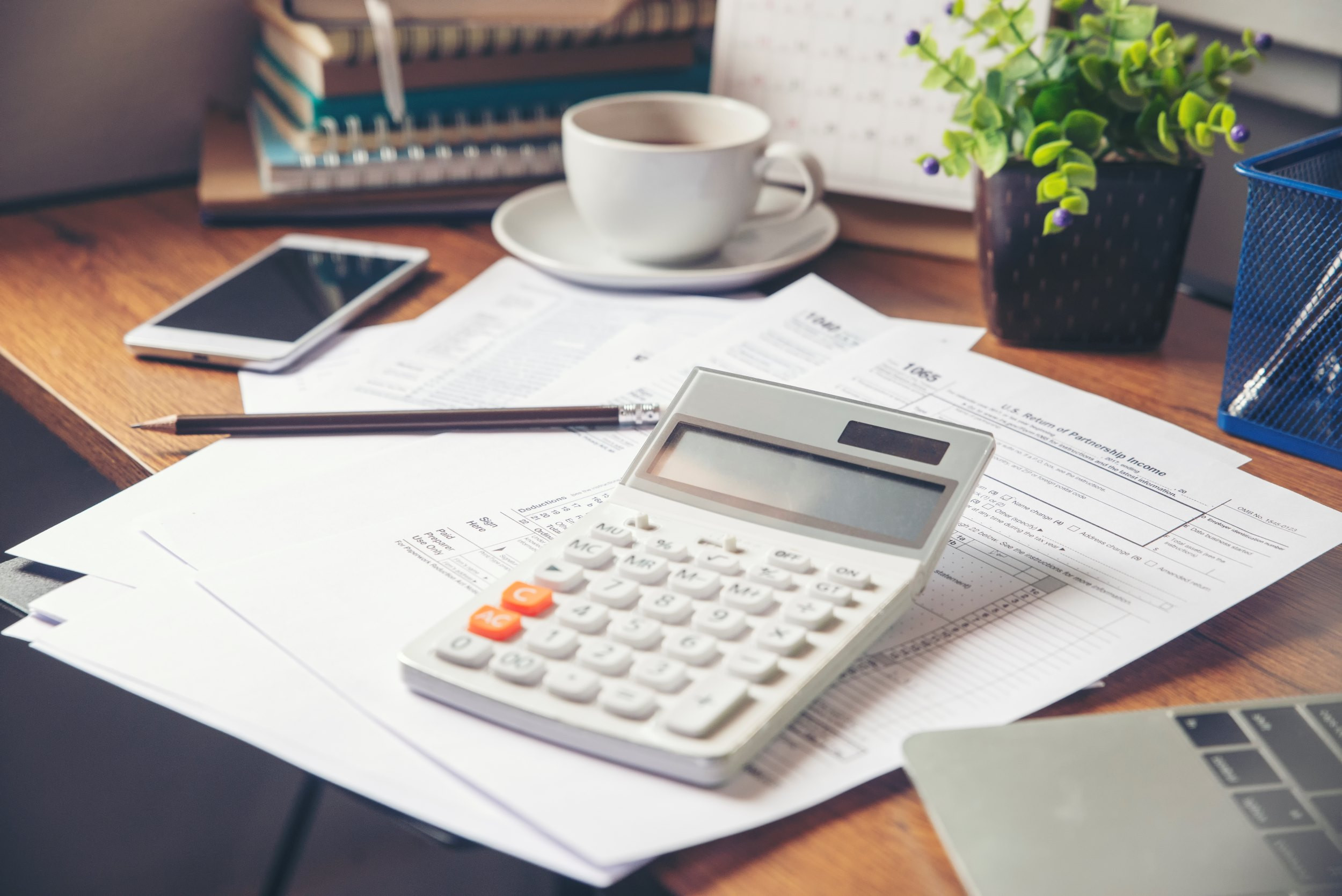 a desk with tax forms, calculator and a phone