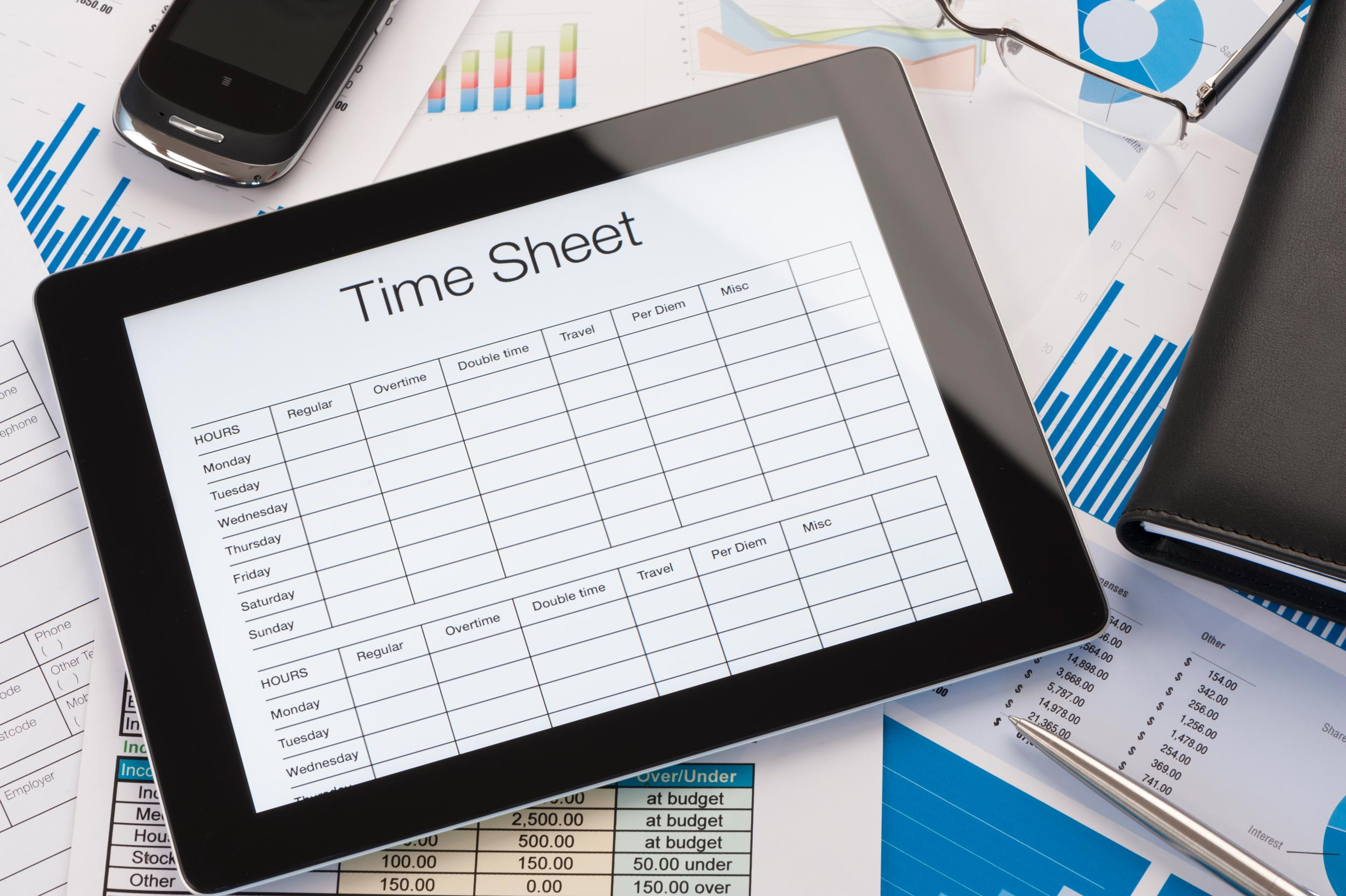 a time sheet tablet on top of payroll documents