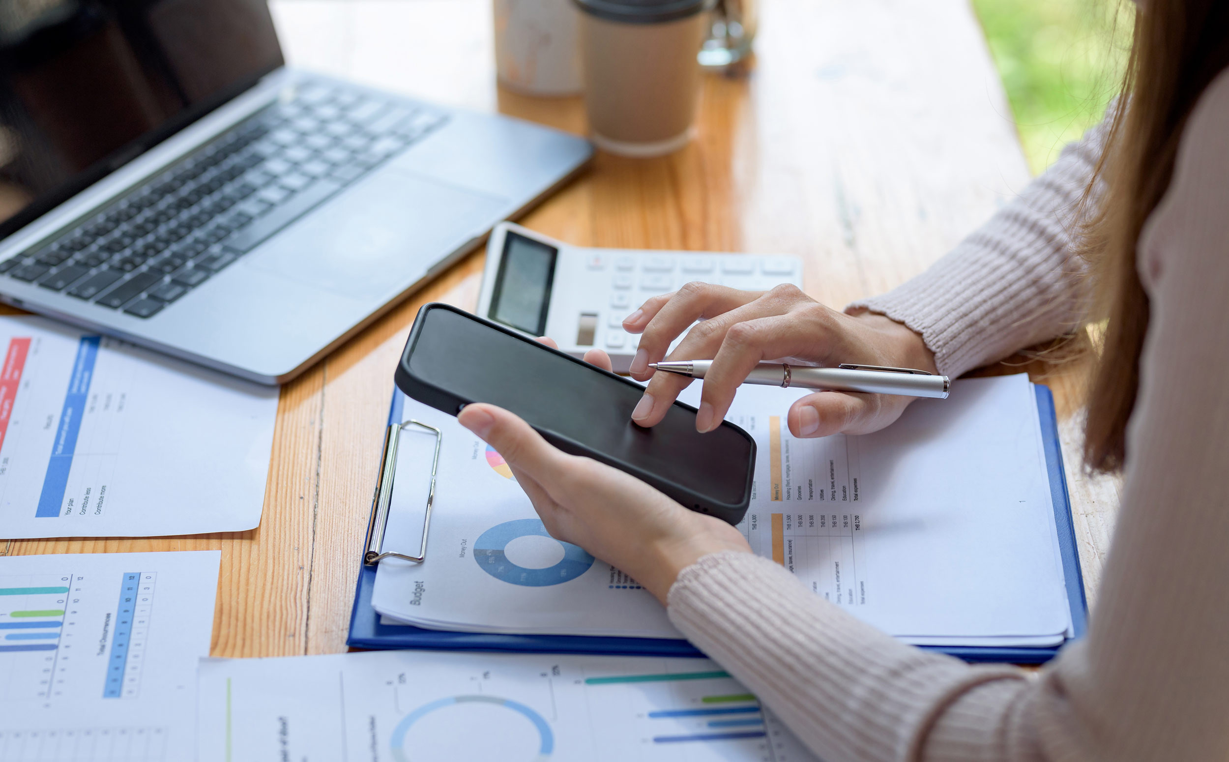 person working on documents with a phone and laptop