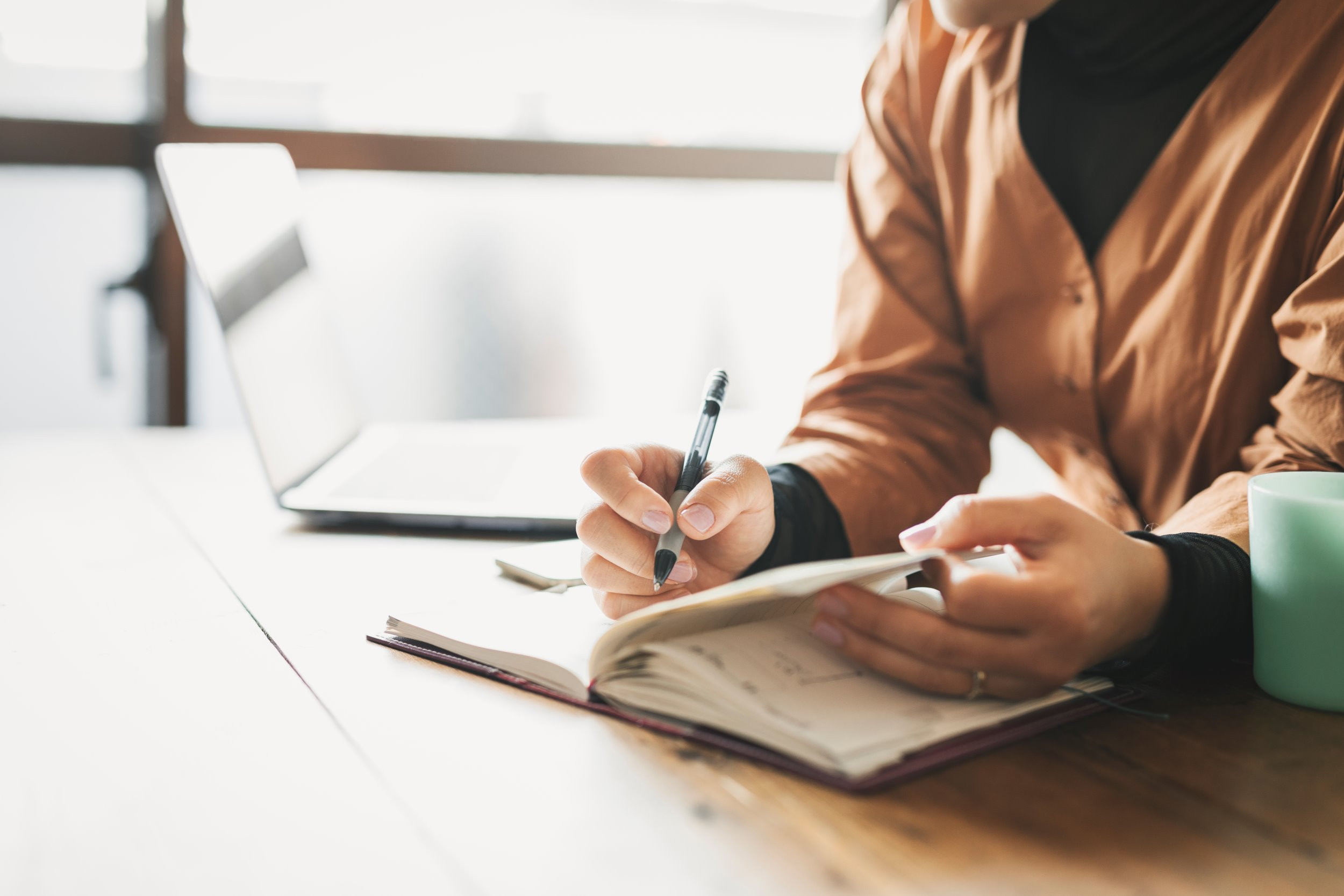 person writing down notes from the computer