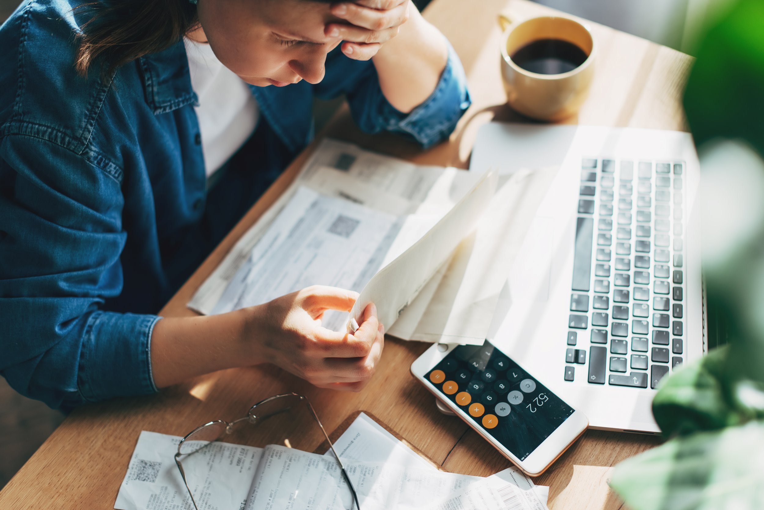 person looking over bills and documents with head in hand