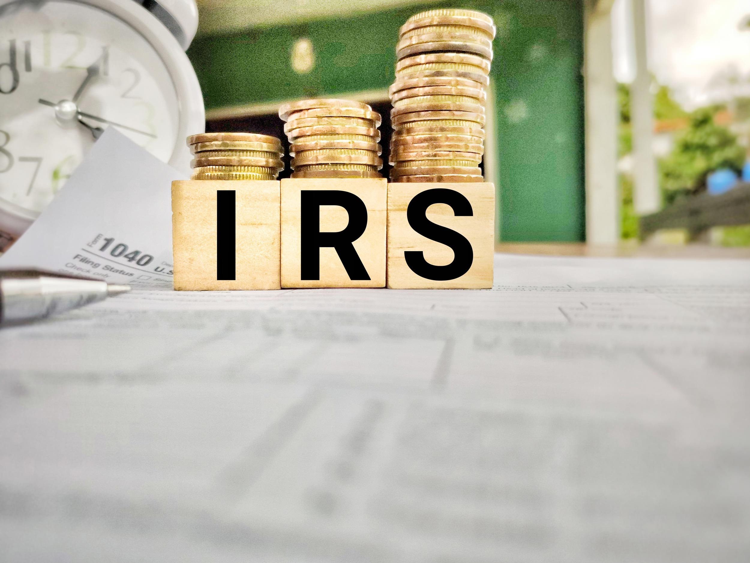 irs blocks with coins and alarm clock on the tax form
