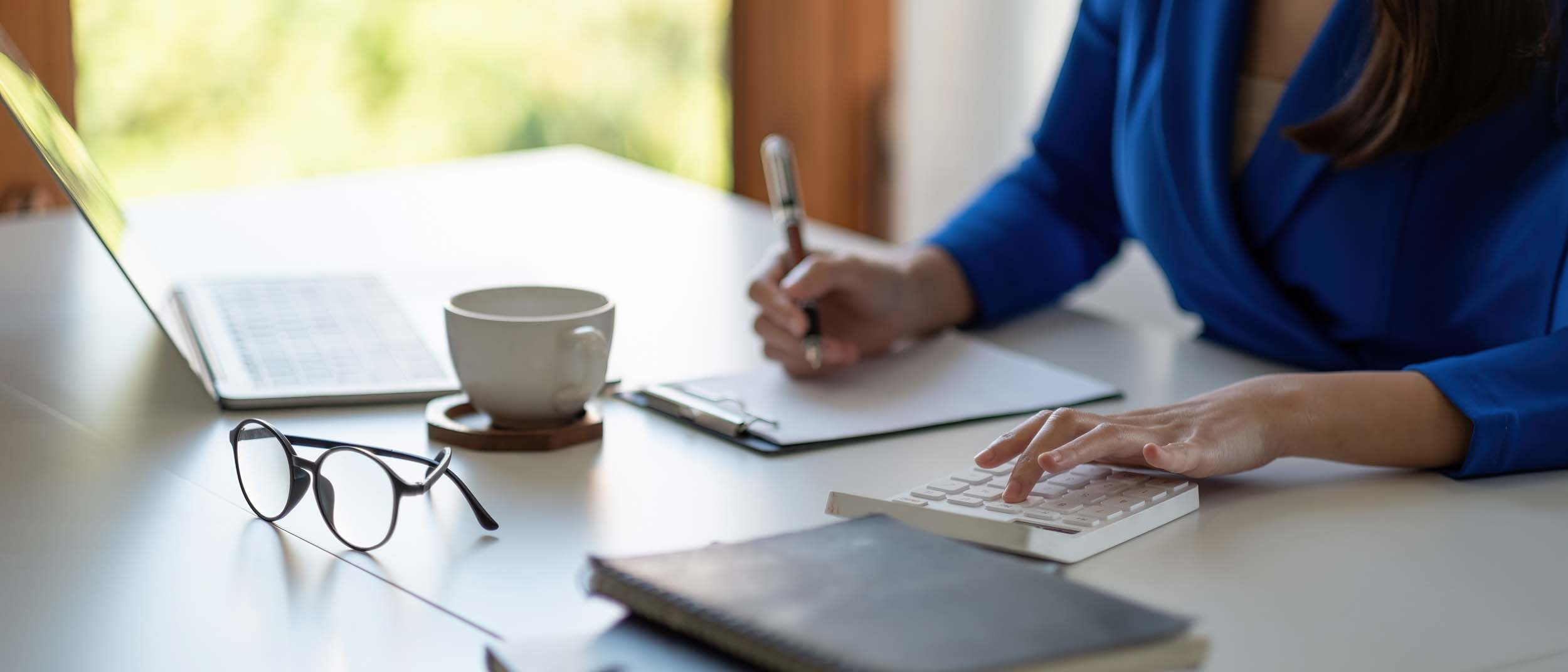 a businessperson calculating the accounts using the calculator and laptop