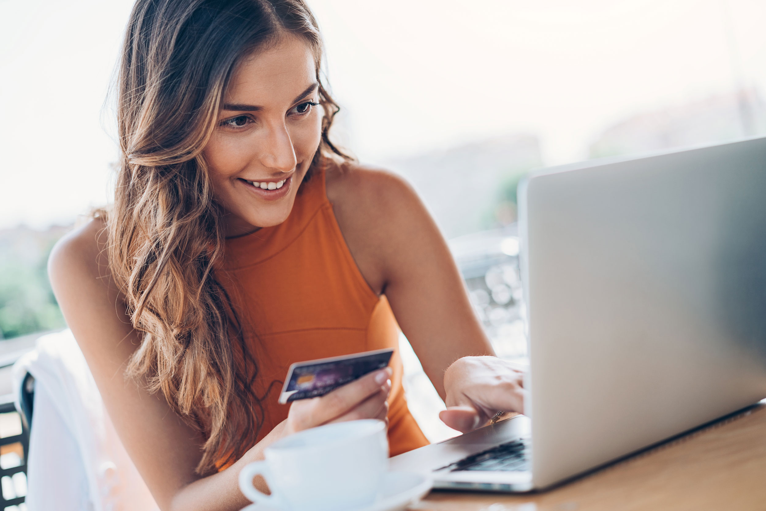 Person holding a credit card over a laptop keyboard