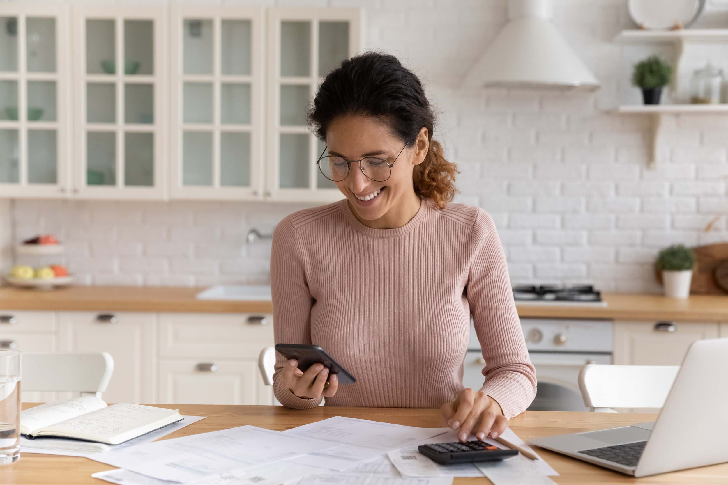 a person doing accounting with phone laptop and calculator