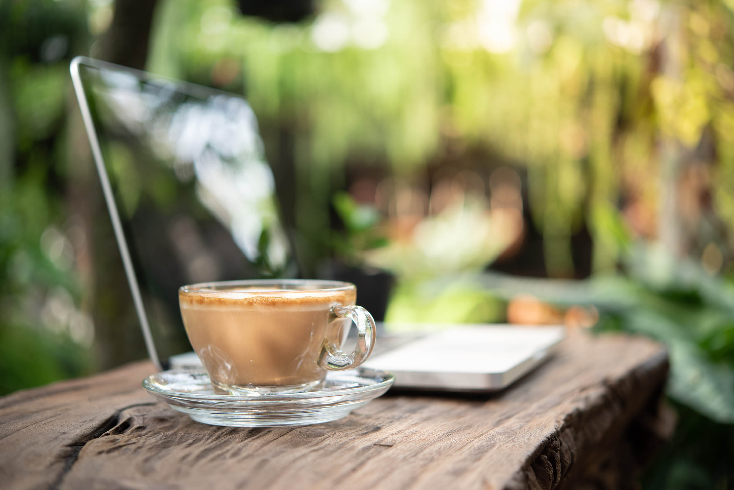 cup of coffee on wooden tabletop on computer