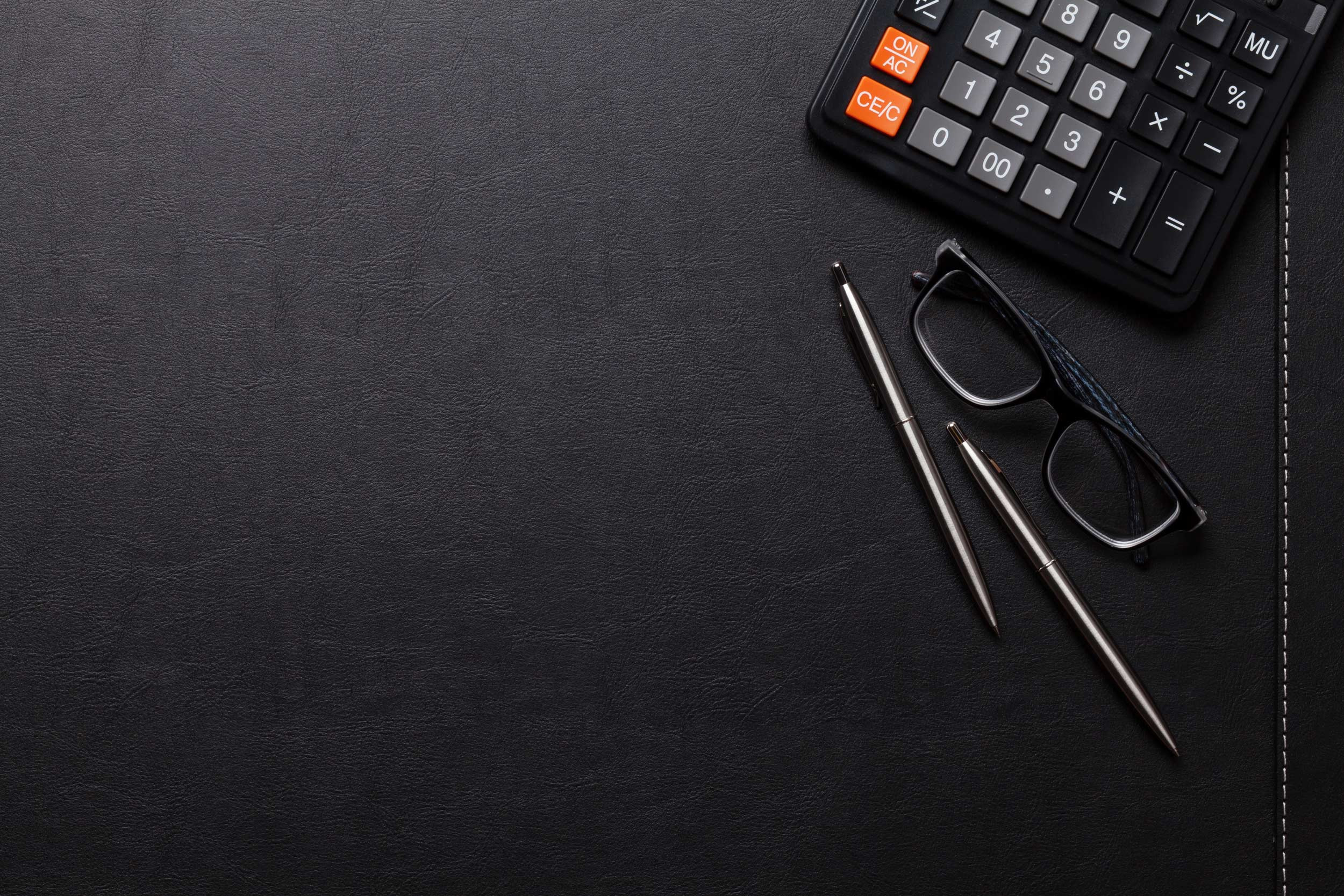 calculator, pen and eyeglass with leather desktop