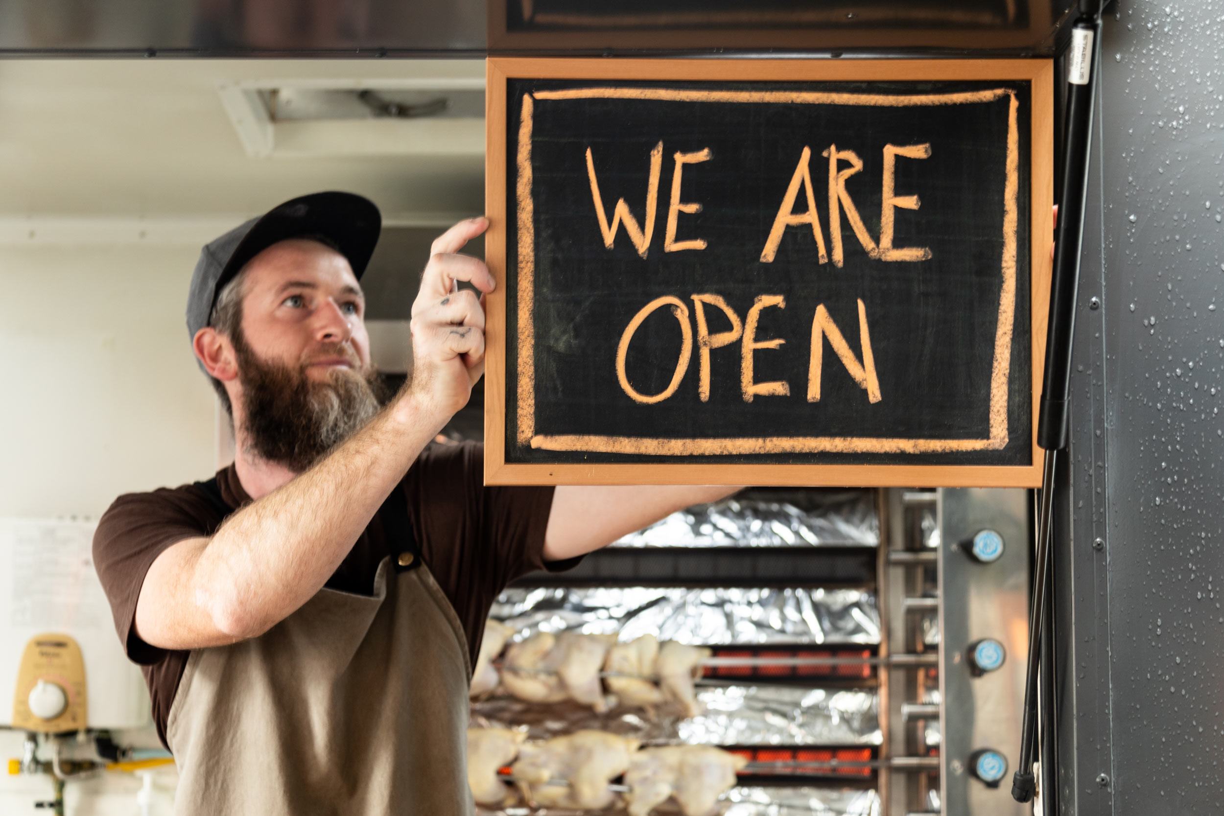 a person hanging the we are open sign board in the edge of glass door