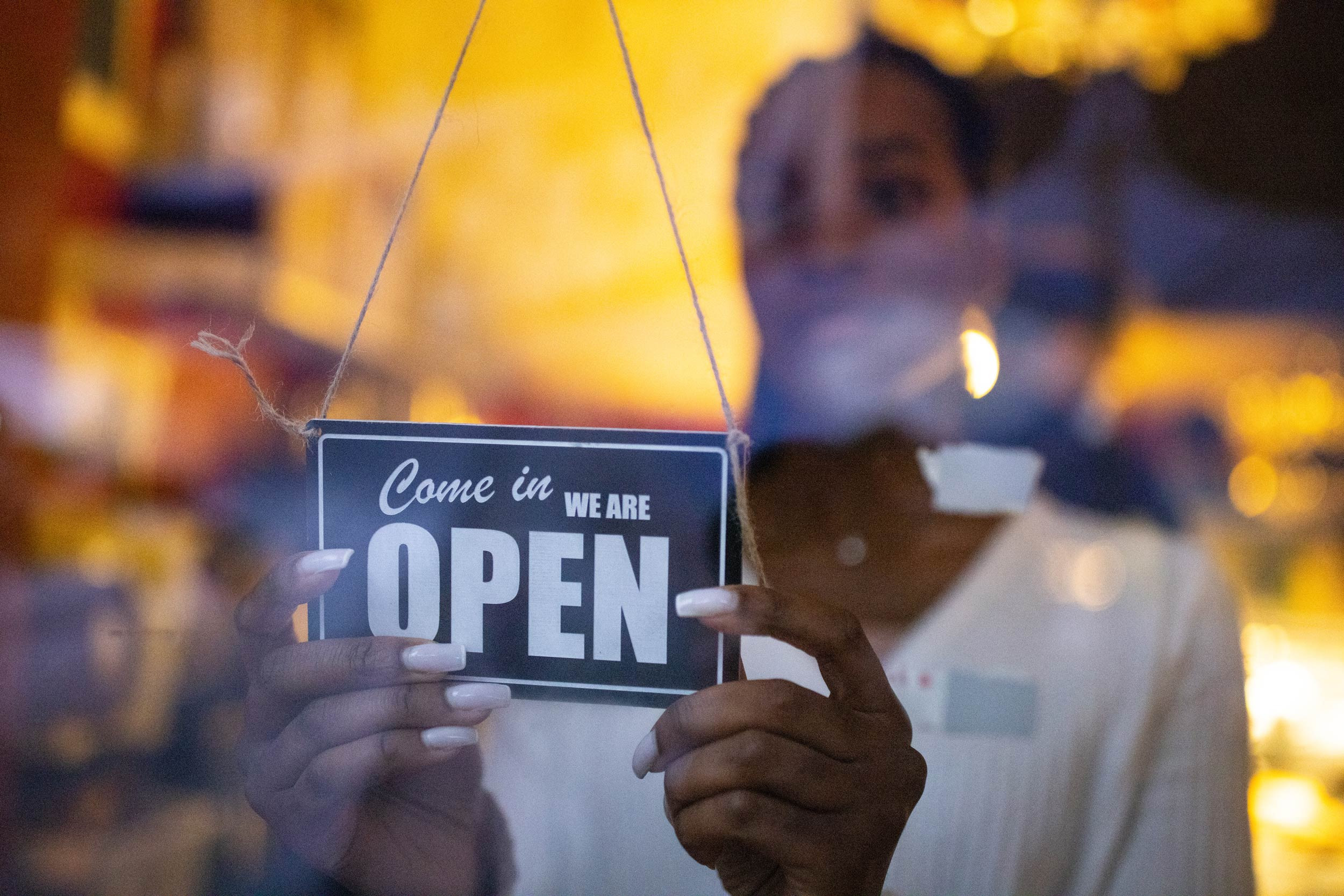 a person adjusting the business open sign board