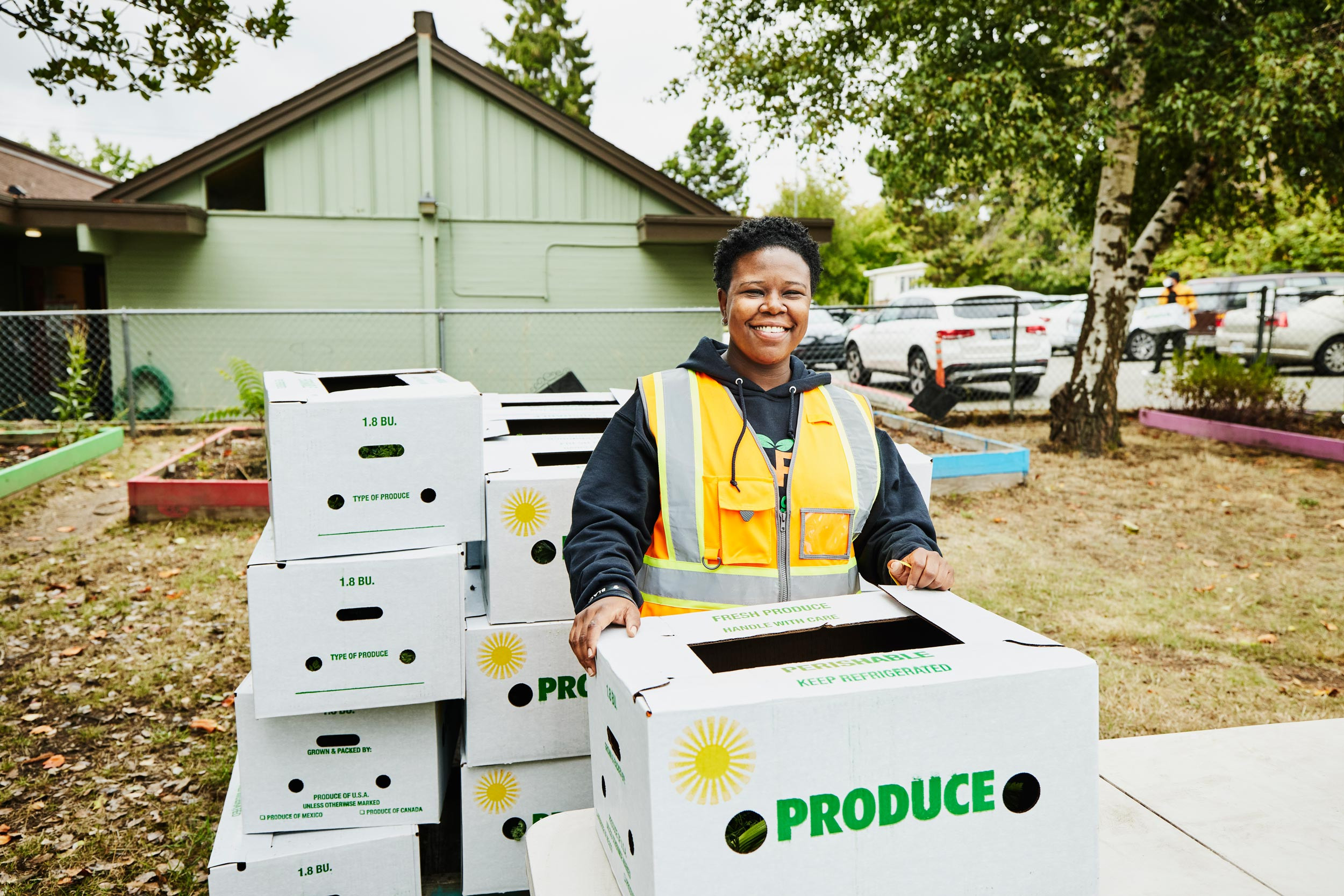 a volunteer person smiling at community center giving away csa boxes