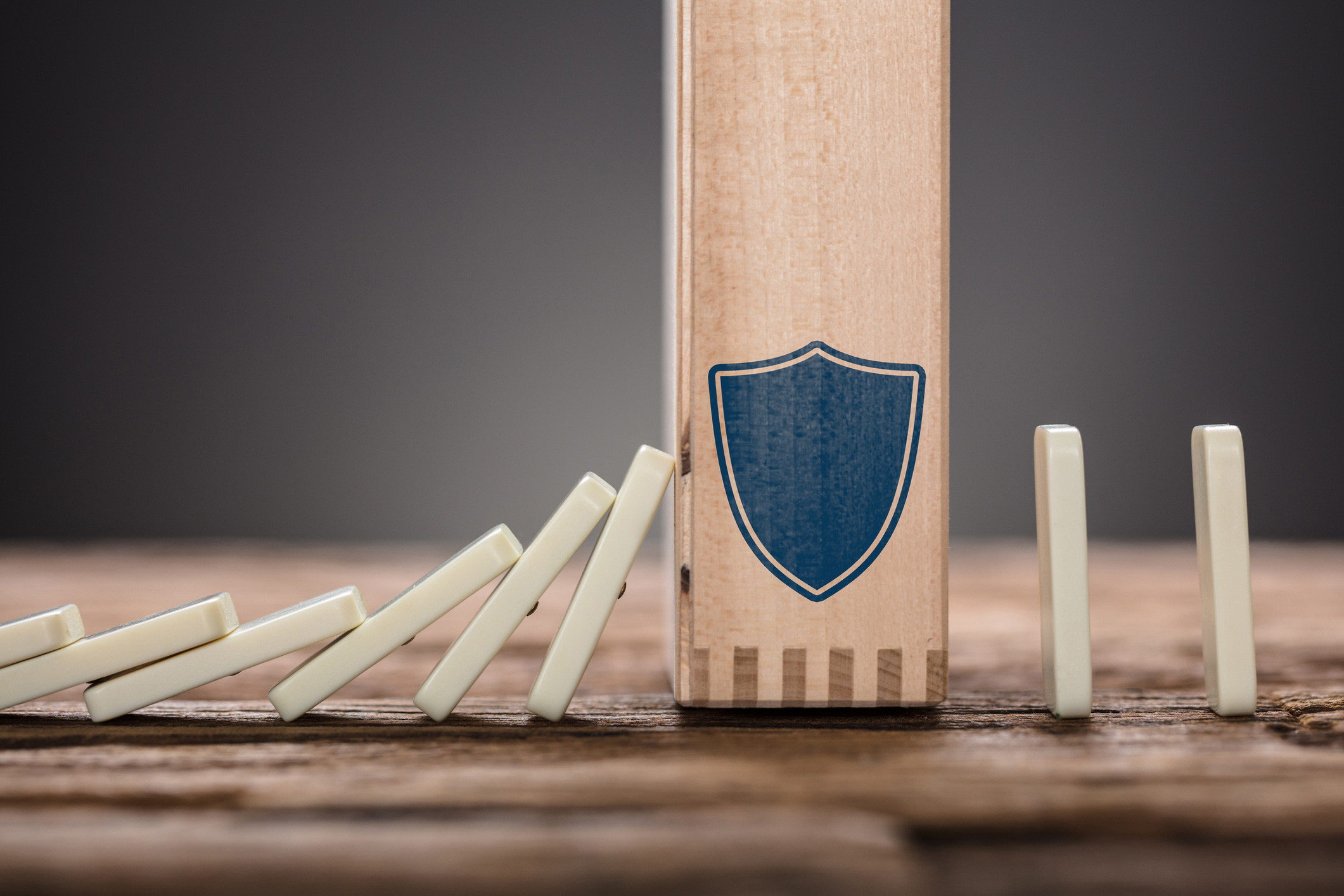 block with shield symbol amidst falling domino pieces