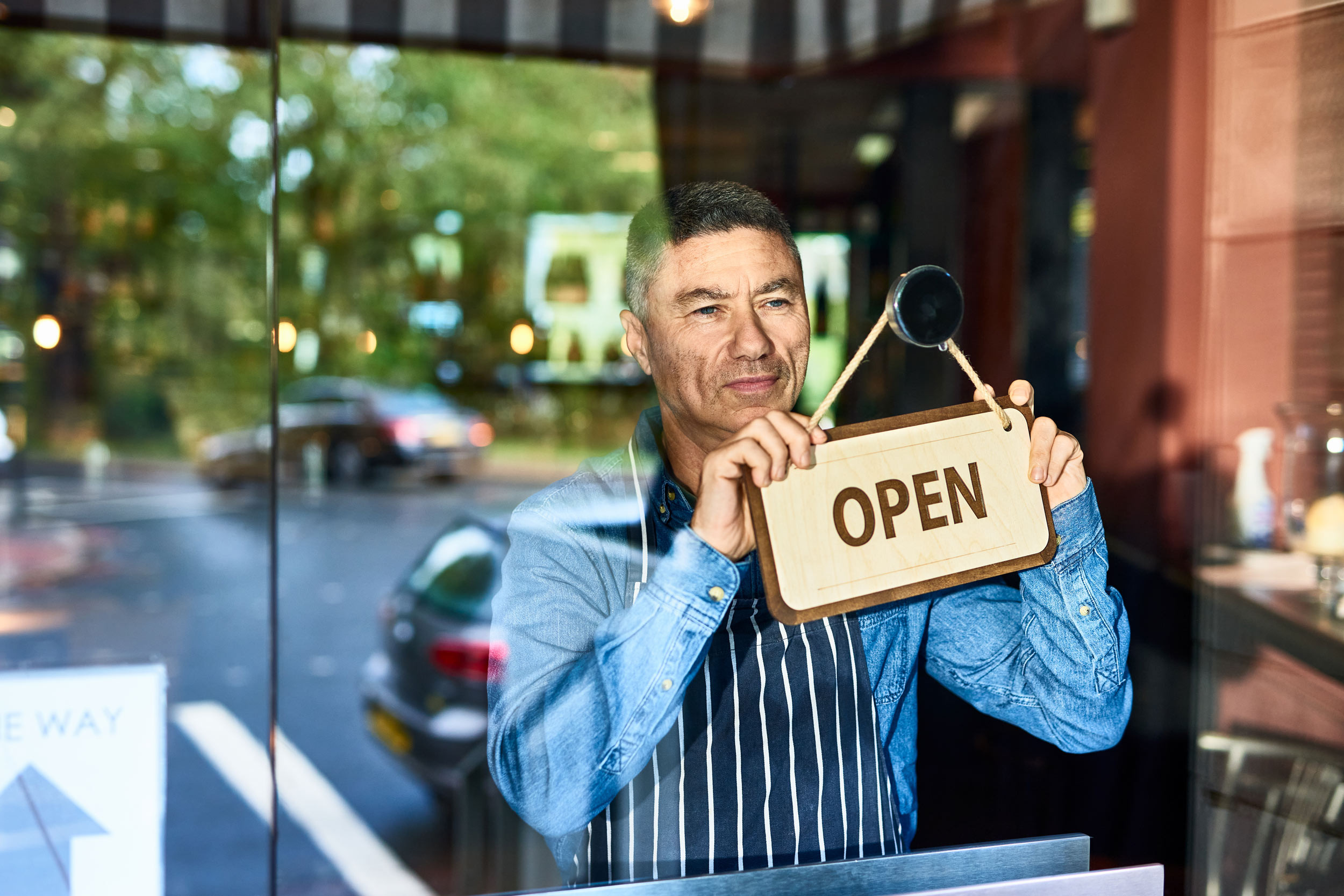 a small business owner hanging the open sign board
