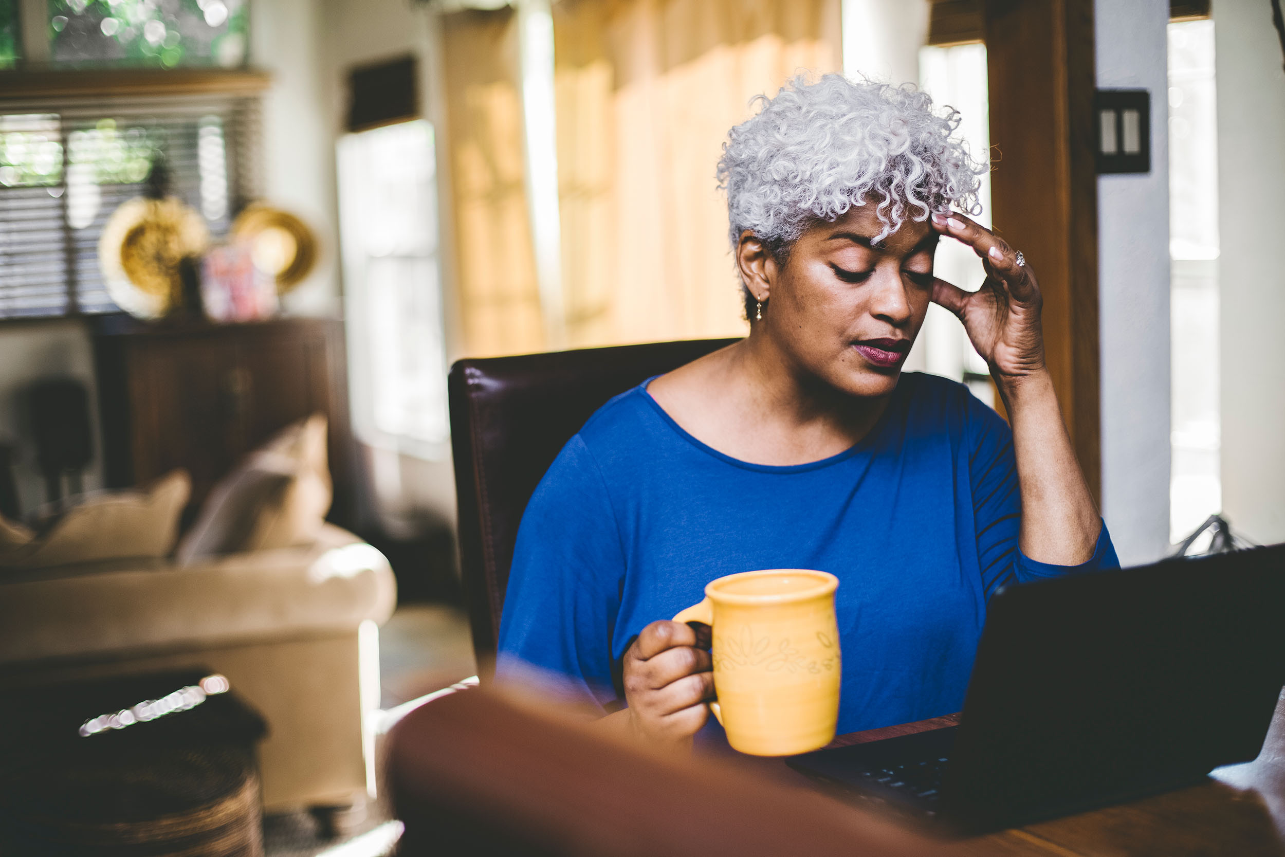 stressed person drinking a cup of coffee and using laptop