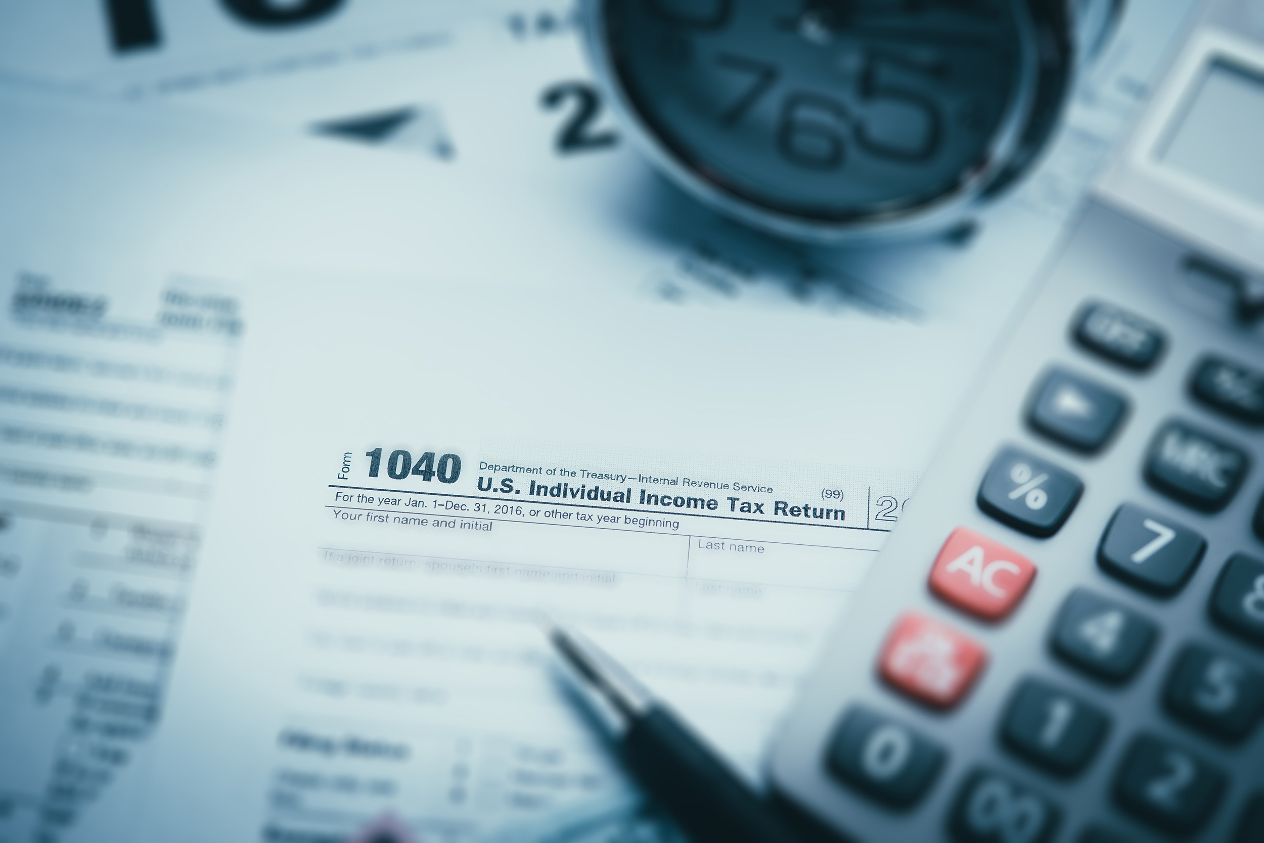 tax form 1040 with pen, calculator and alarm clock
